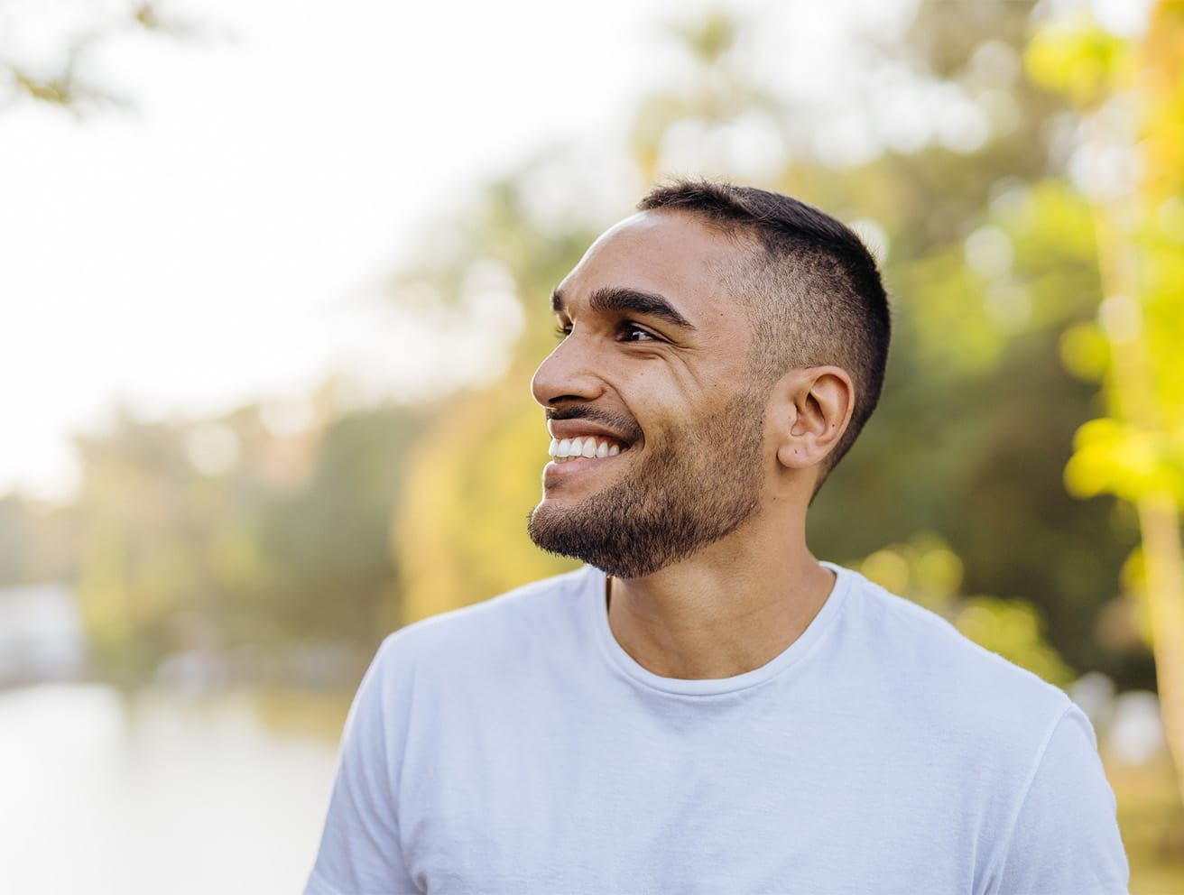 man standing by a lake, smiling