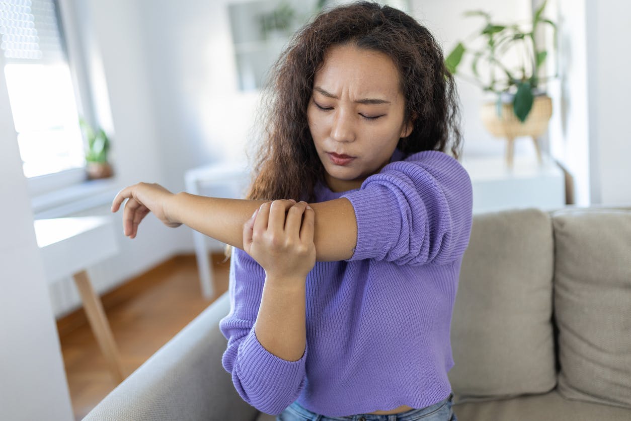 asian woman in purple shirt holding her arm up