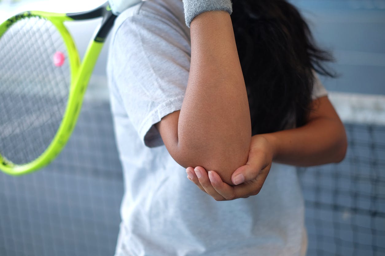 woman holding racket and her elbow