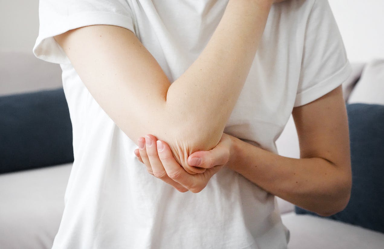 person in white shirt holding their elbow
