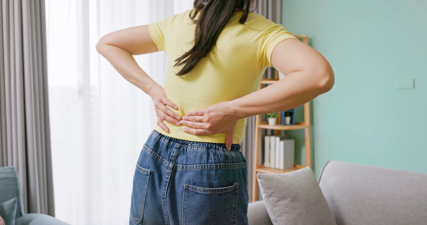 woman in yellow shirt holding her back