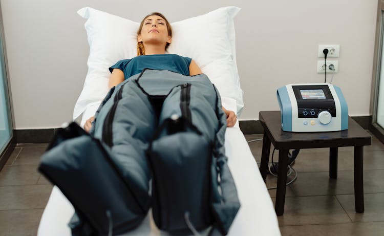 lady laying on hospital bed using leg compression machine