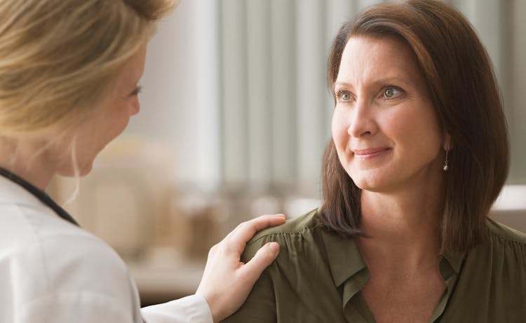 doctor speaking to client with hand on her shoulder