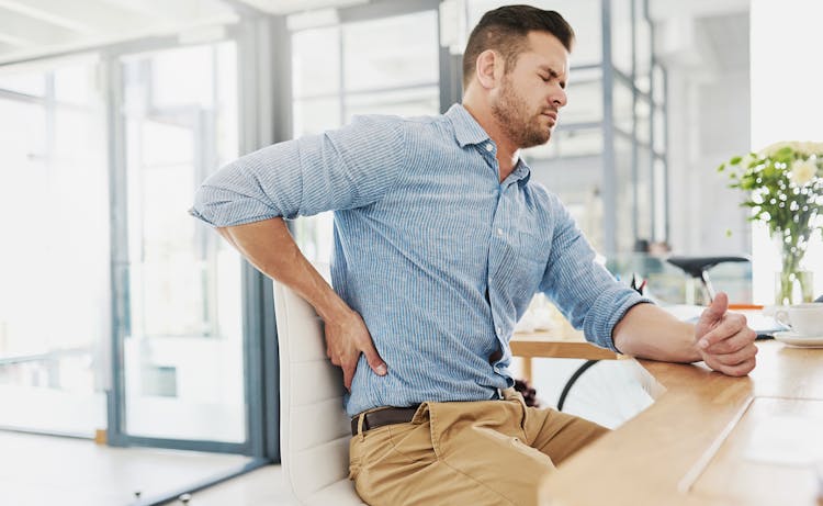 man sitting with hand on back