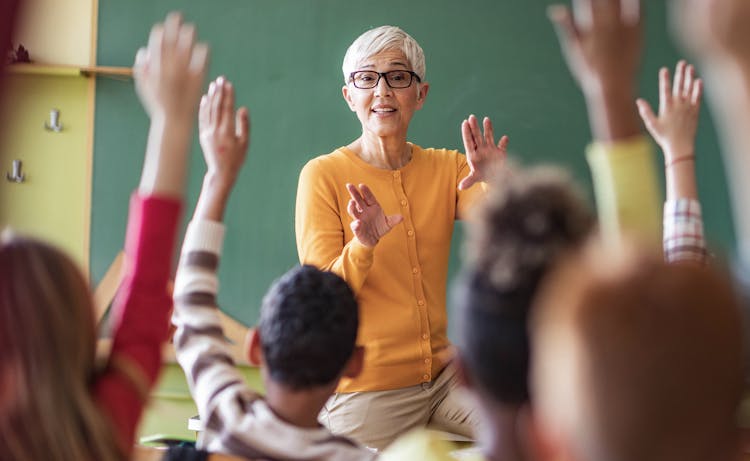 teacher in class with students raising their hands