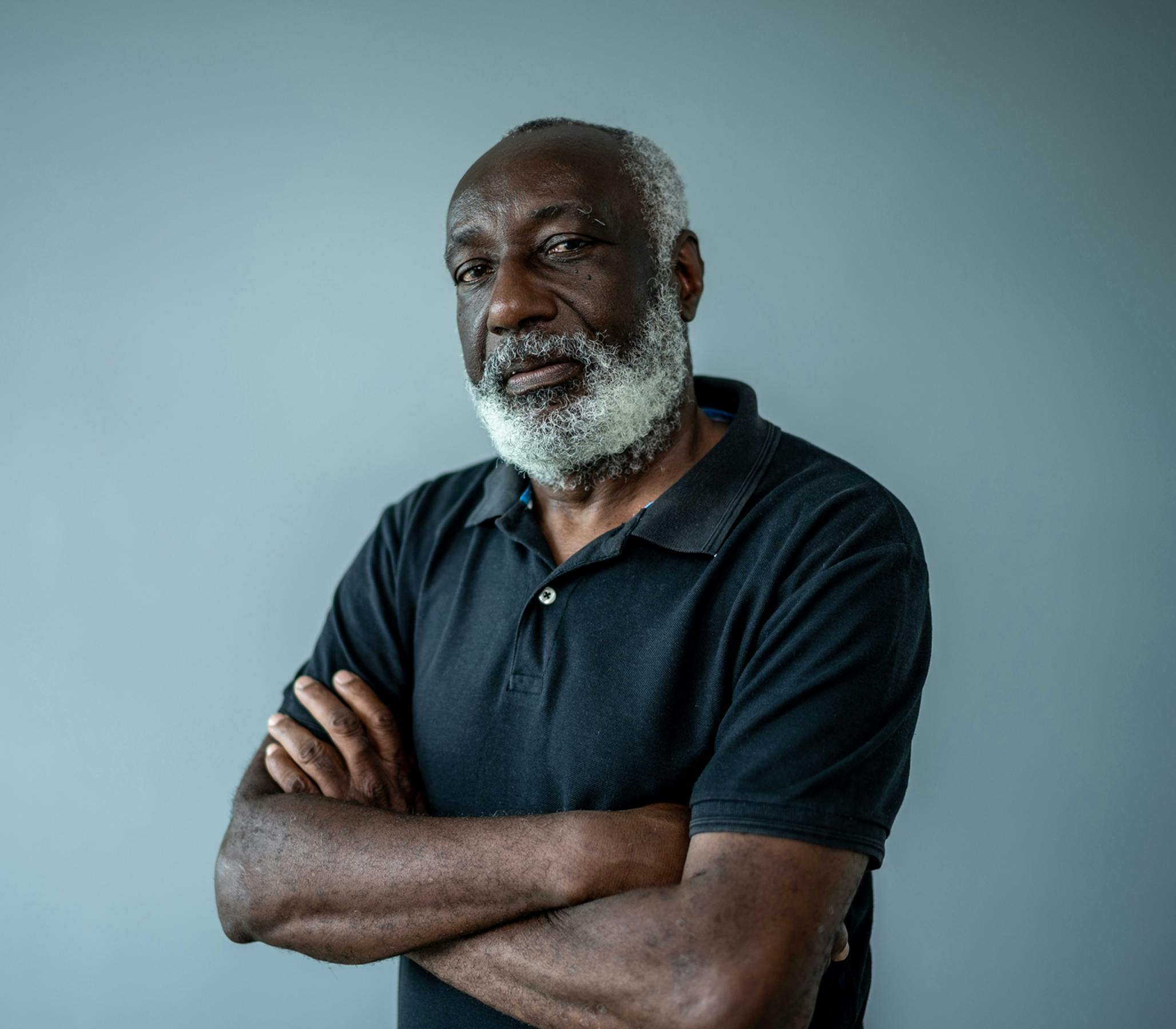 older man crossing arms looking at camera