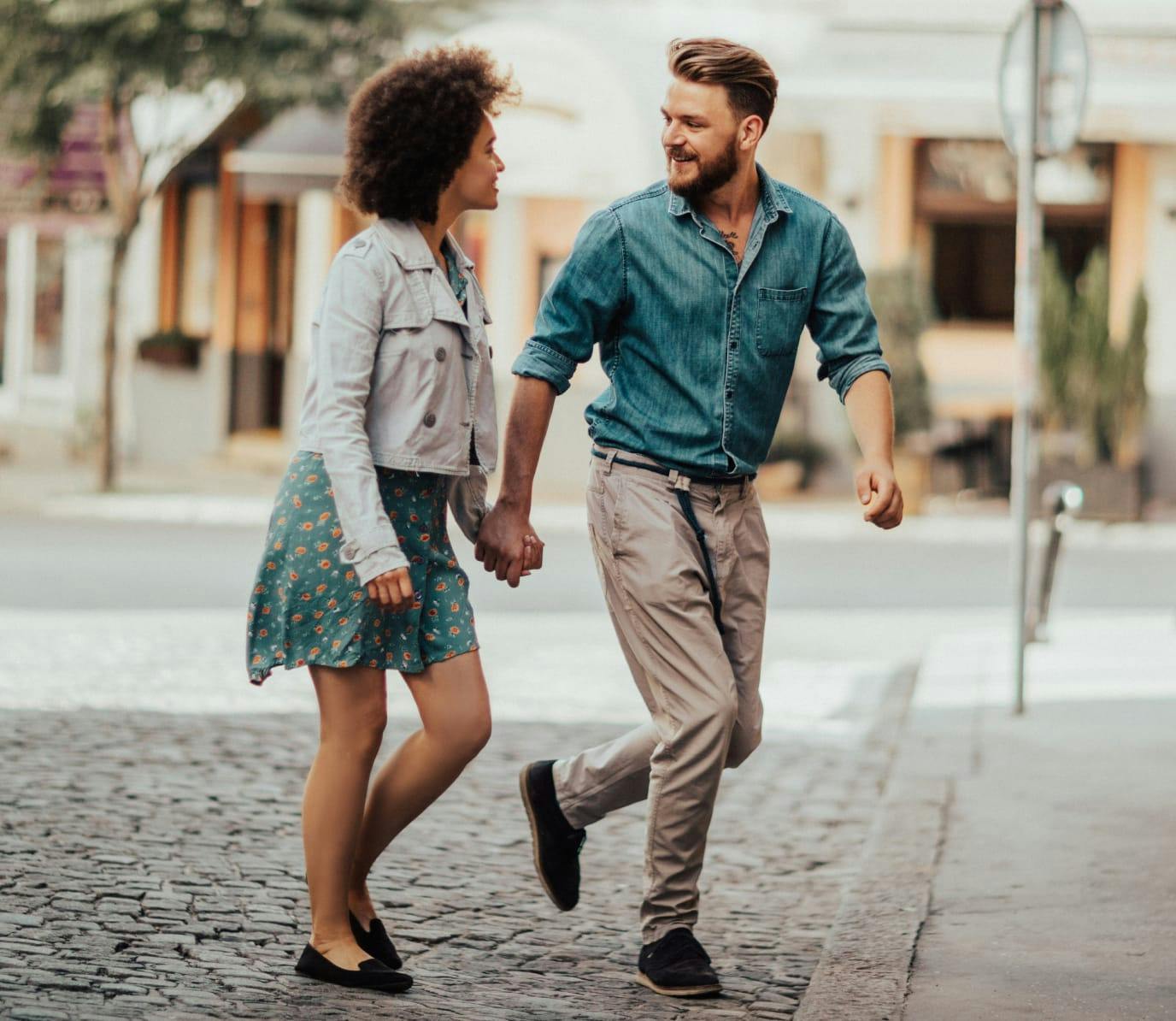 A couple, holding hands, crossing the street