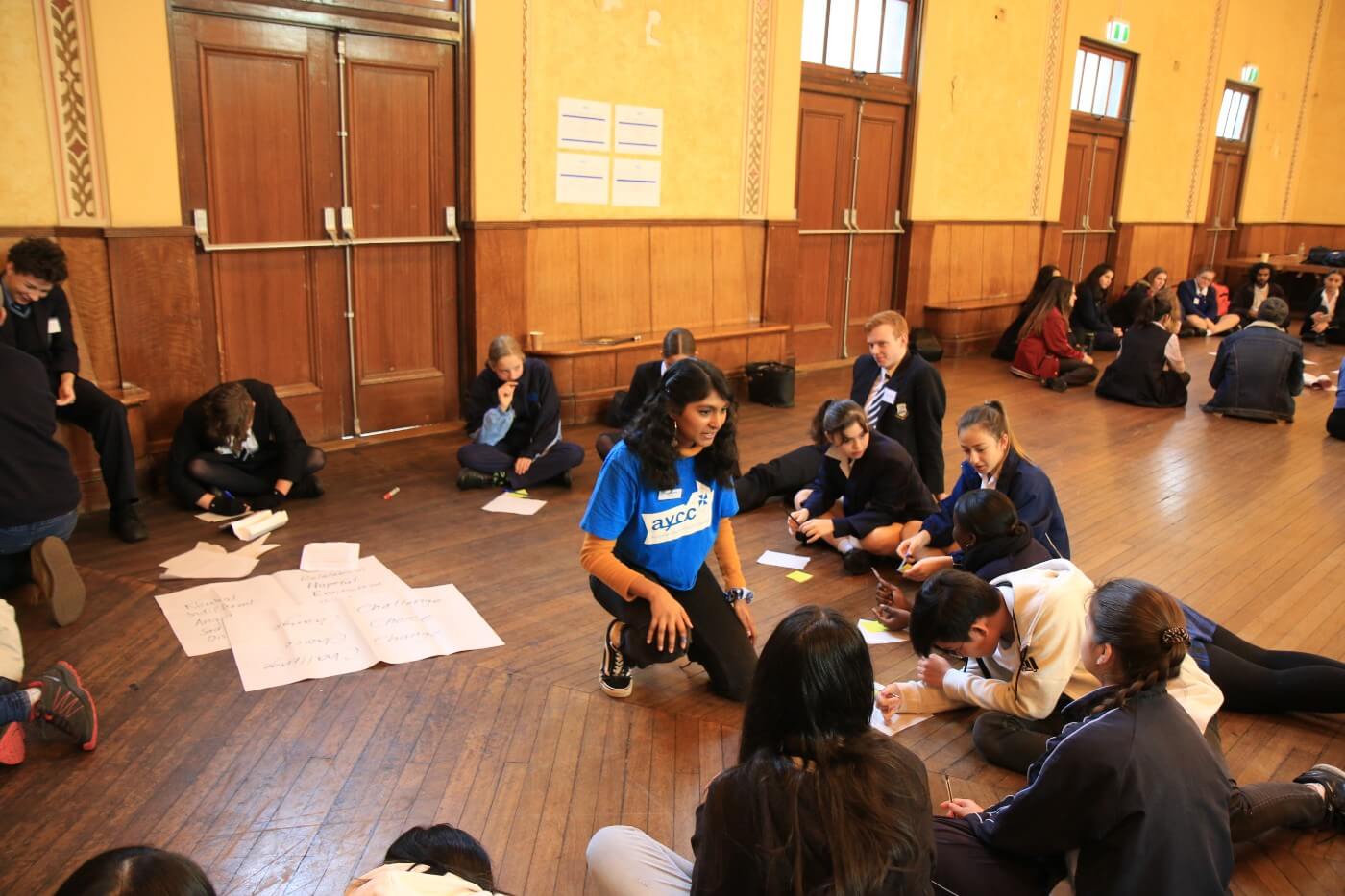 Grace facilitates a workshop with school children in a school hall.