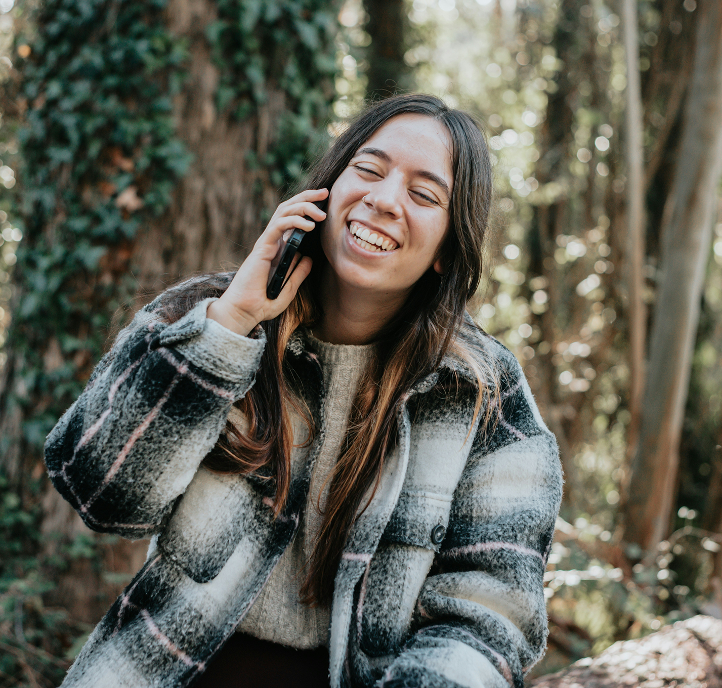 Person on phone smiling in front of trees