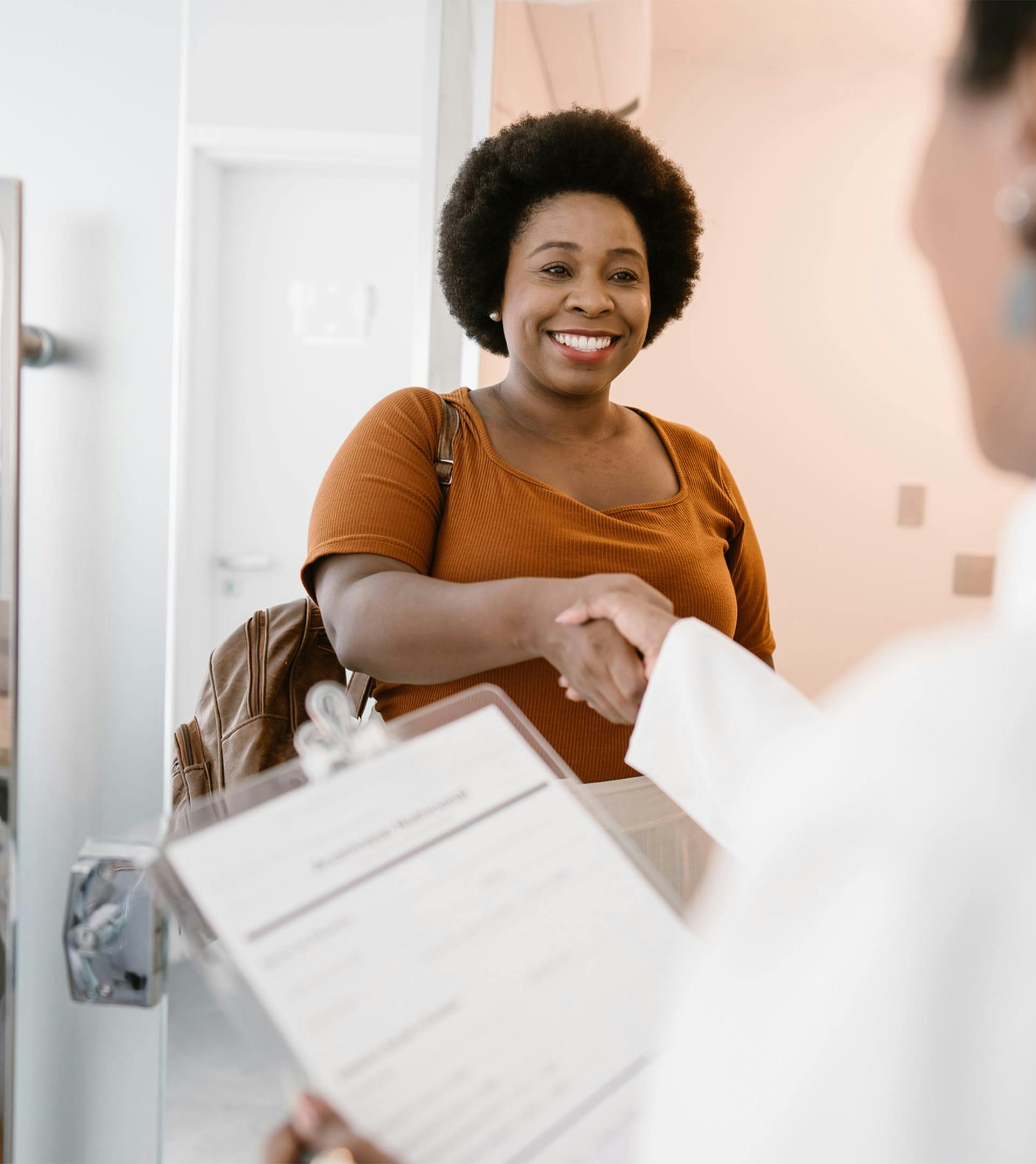woman smiling and shaking someone else's hand