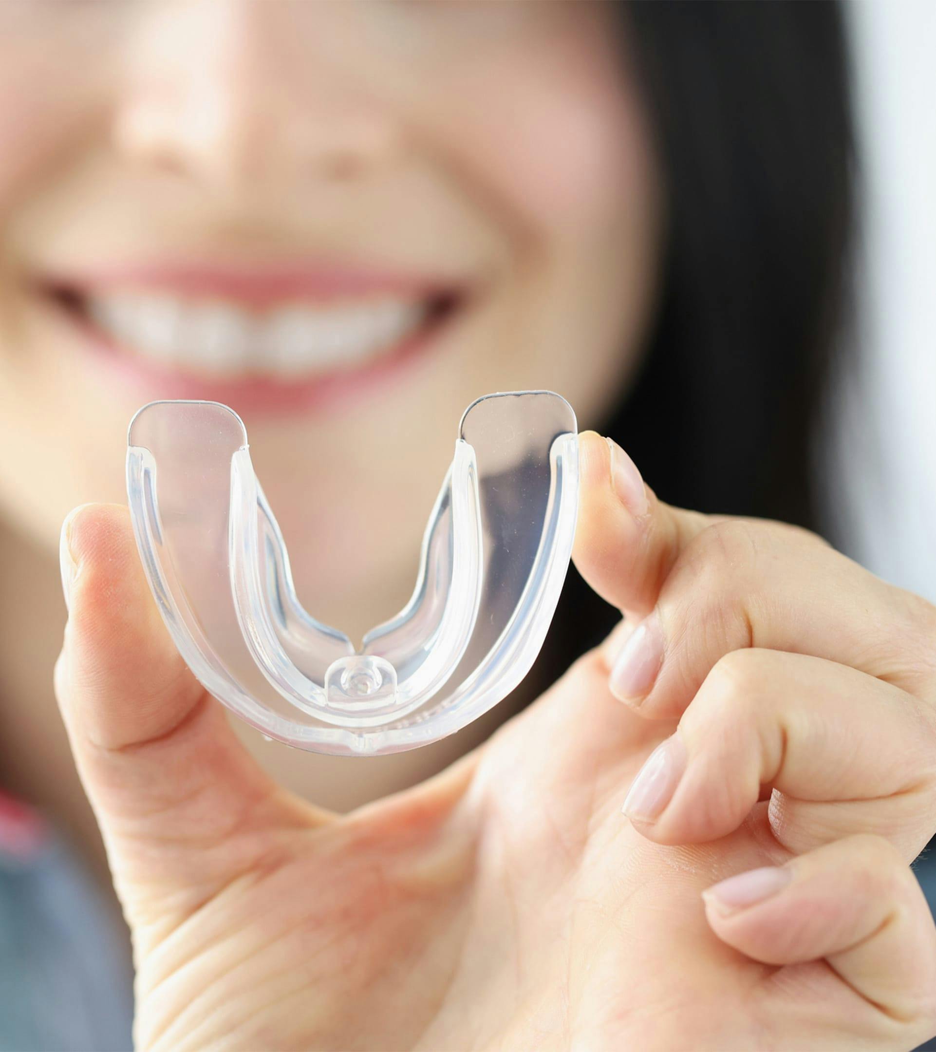 woman holding up teeth guard