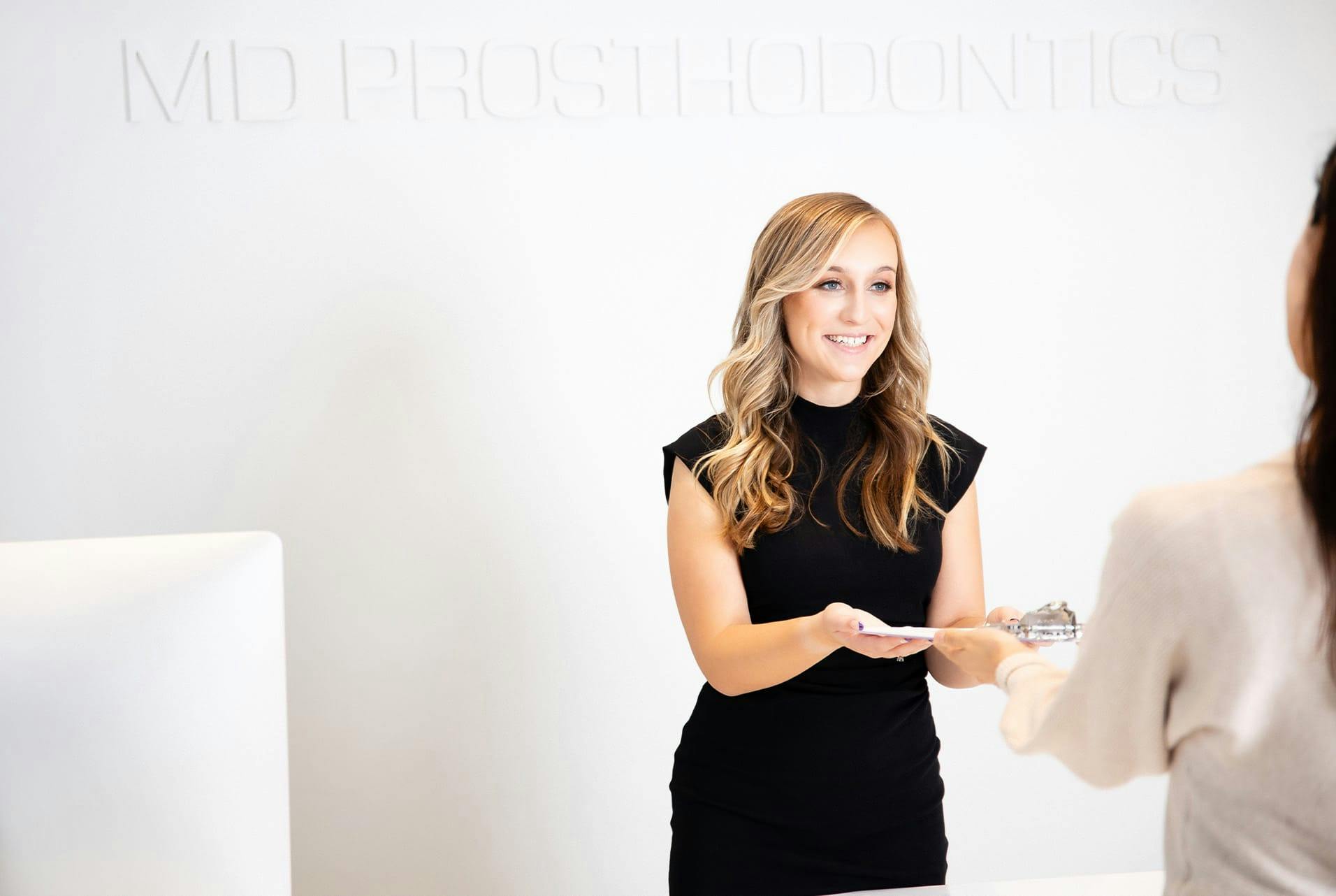 receptionist handing a patient a clipboard