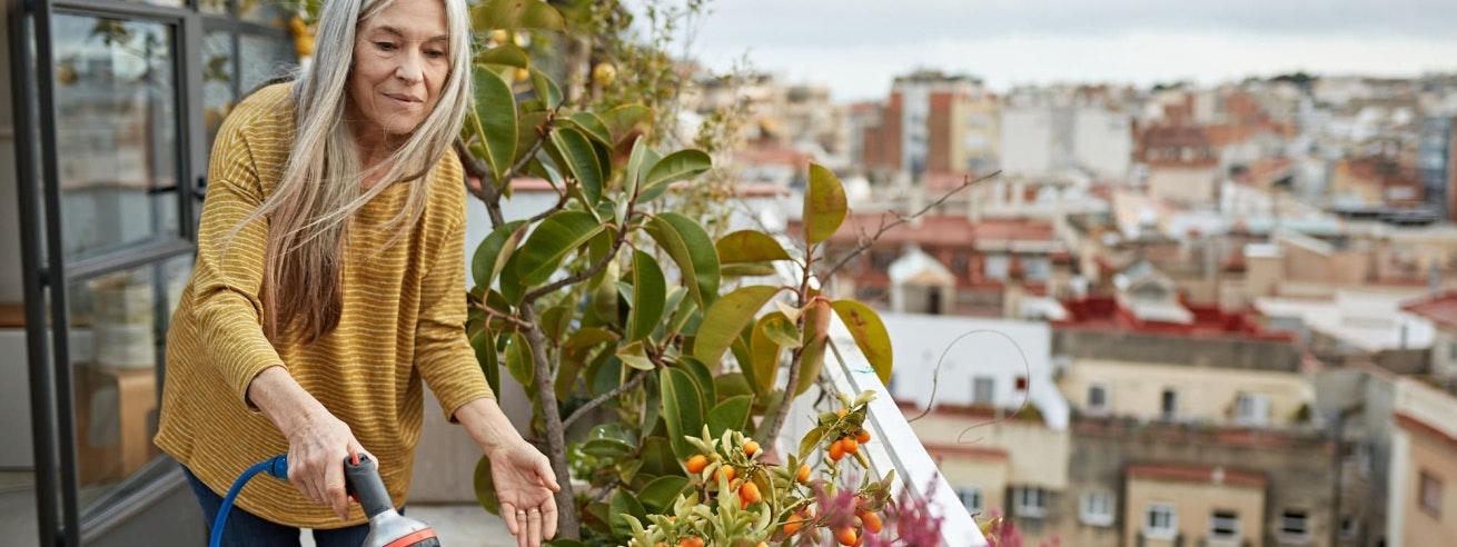 Femme arrosant des plantes sur son balcon