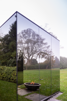 Photo of a mirrored build reflecting a grass lawn and fire pit
