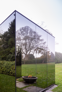 Photo of a mirrored build reflecting a grass lawn and fire pit