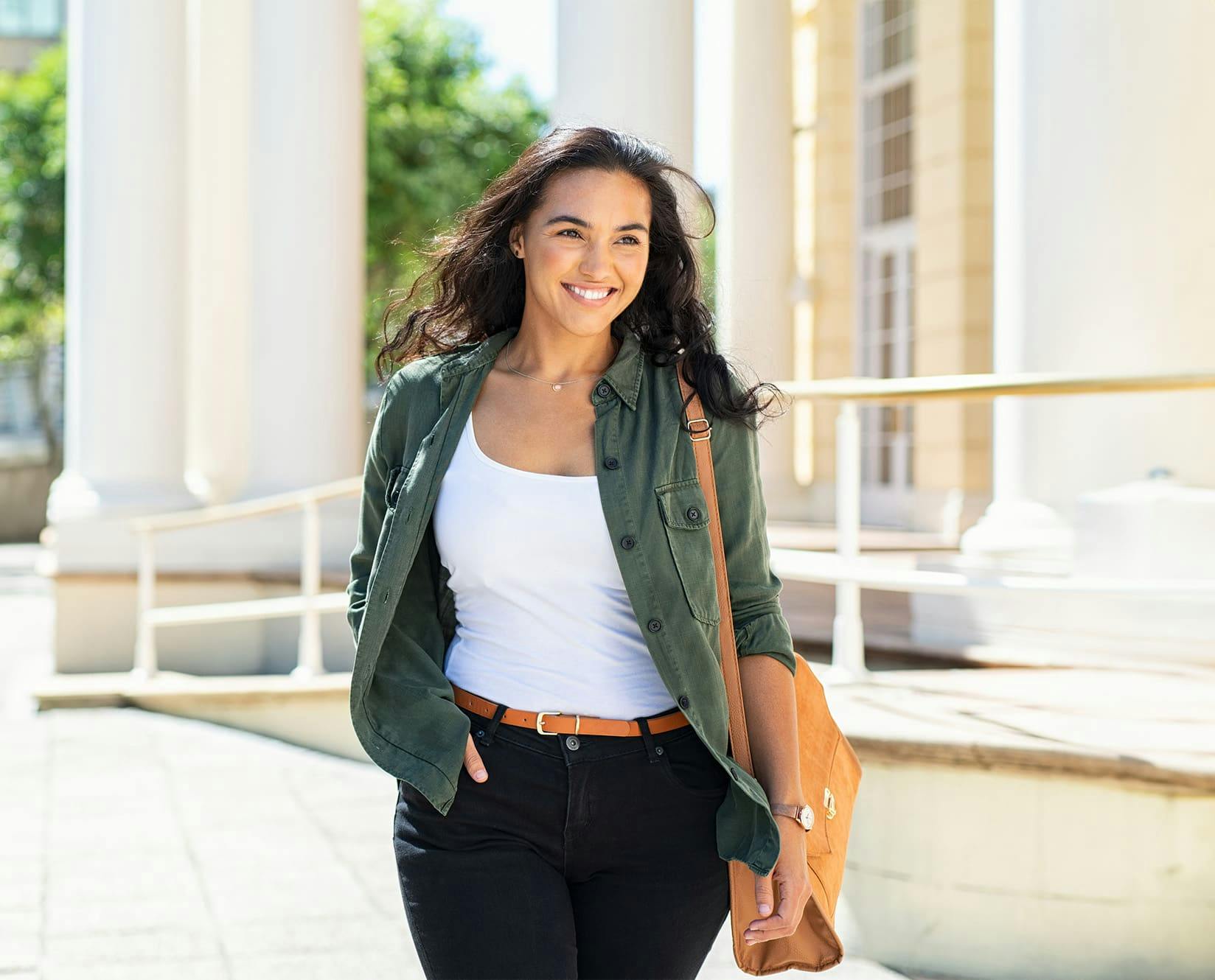 woman outside wearing a white top and green jacket