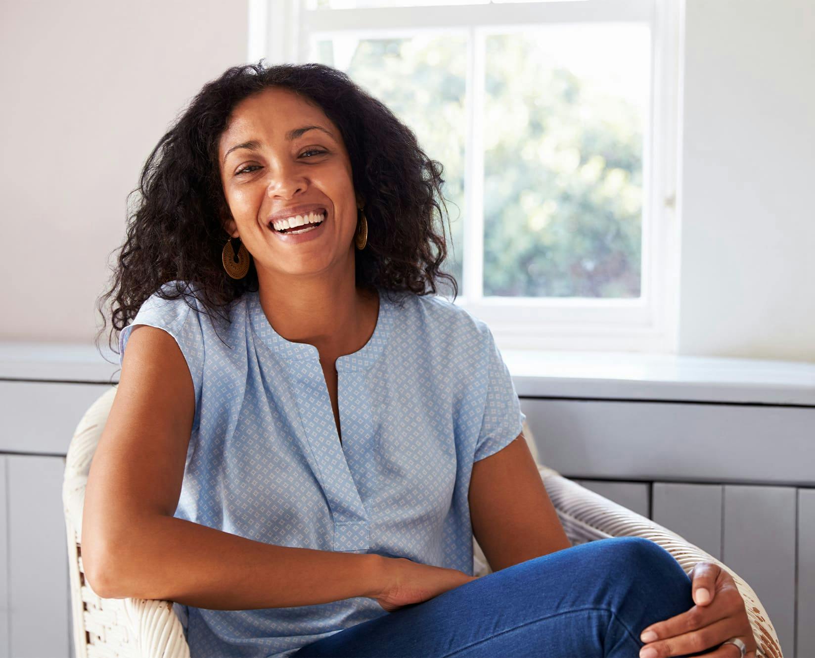 woman in a blue blouse sitting down and smiling