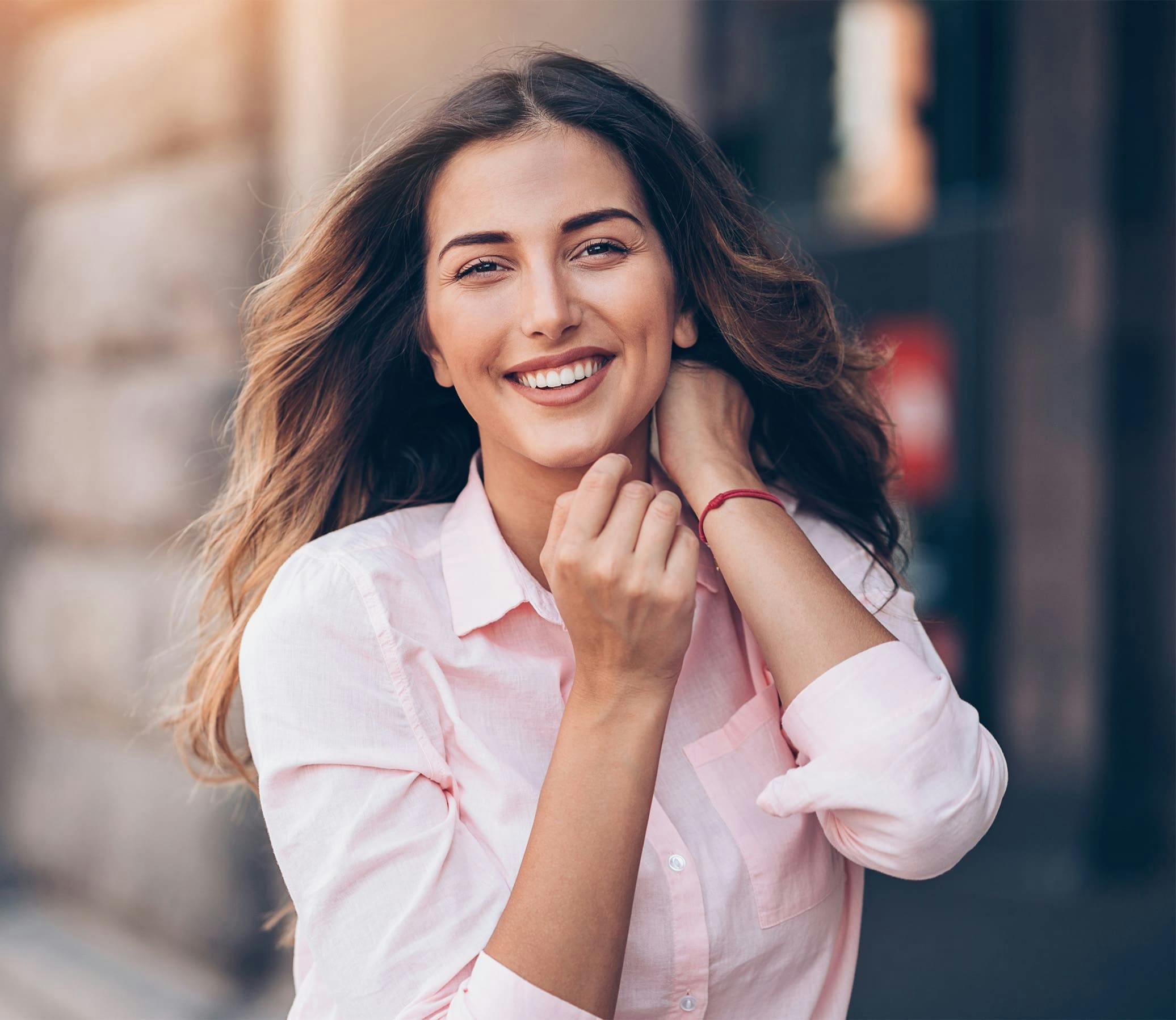 woman in a pink button up shirt outside