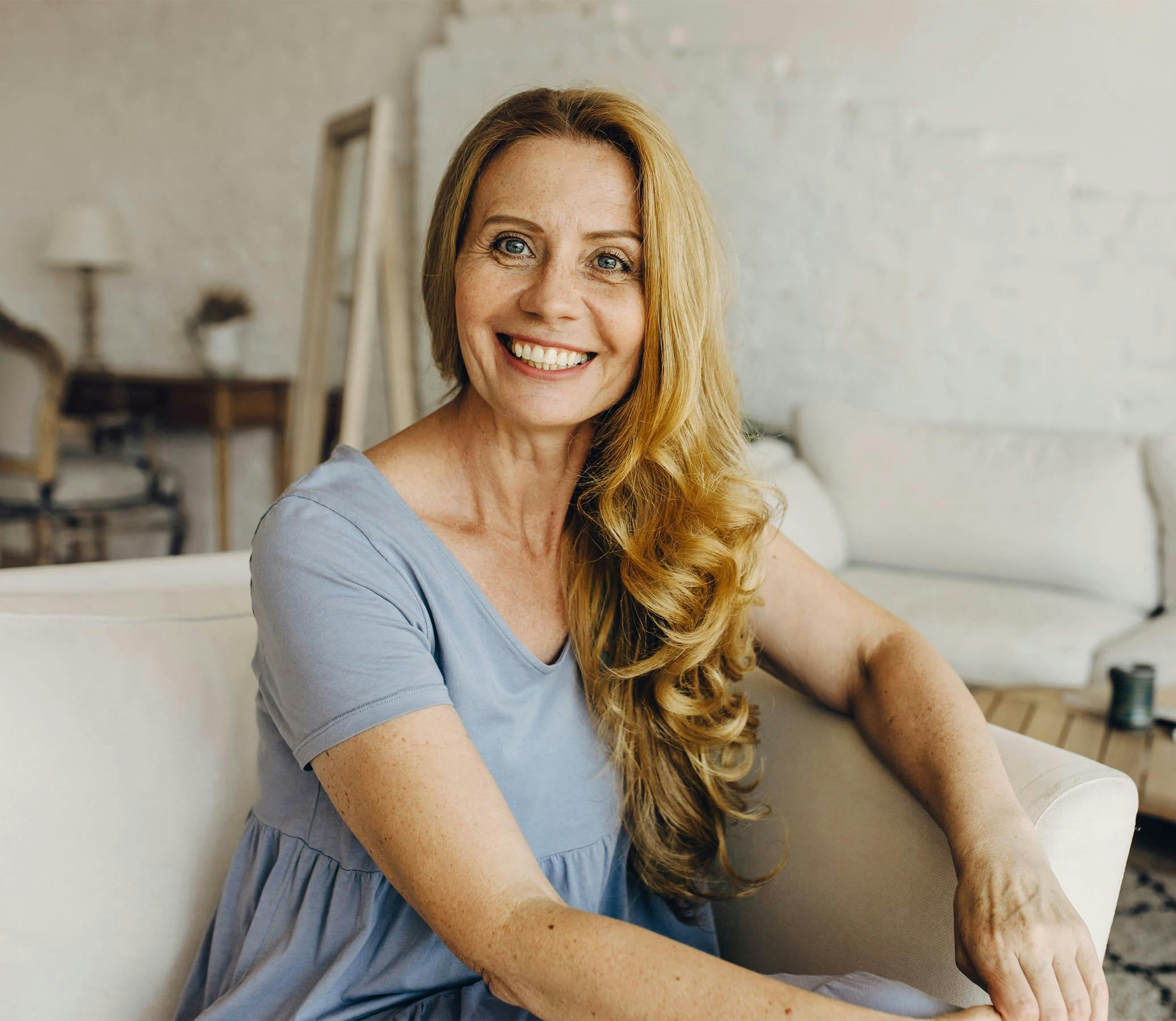 woman with blonde curly hair wearing a blue shirt