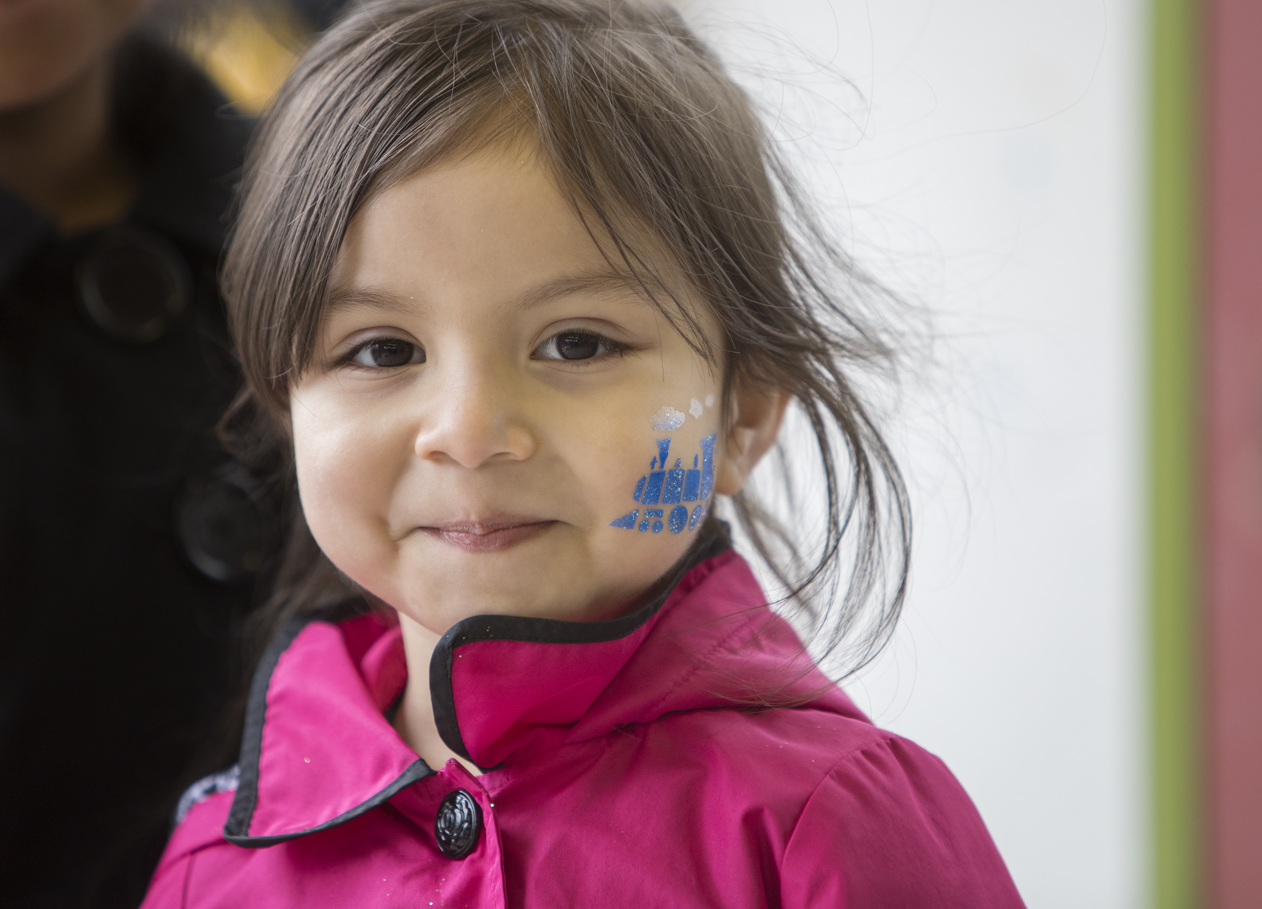 A girl with a detailed glittery blue train painted on the side of her face.