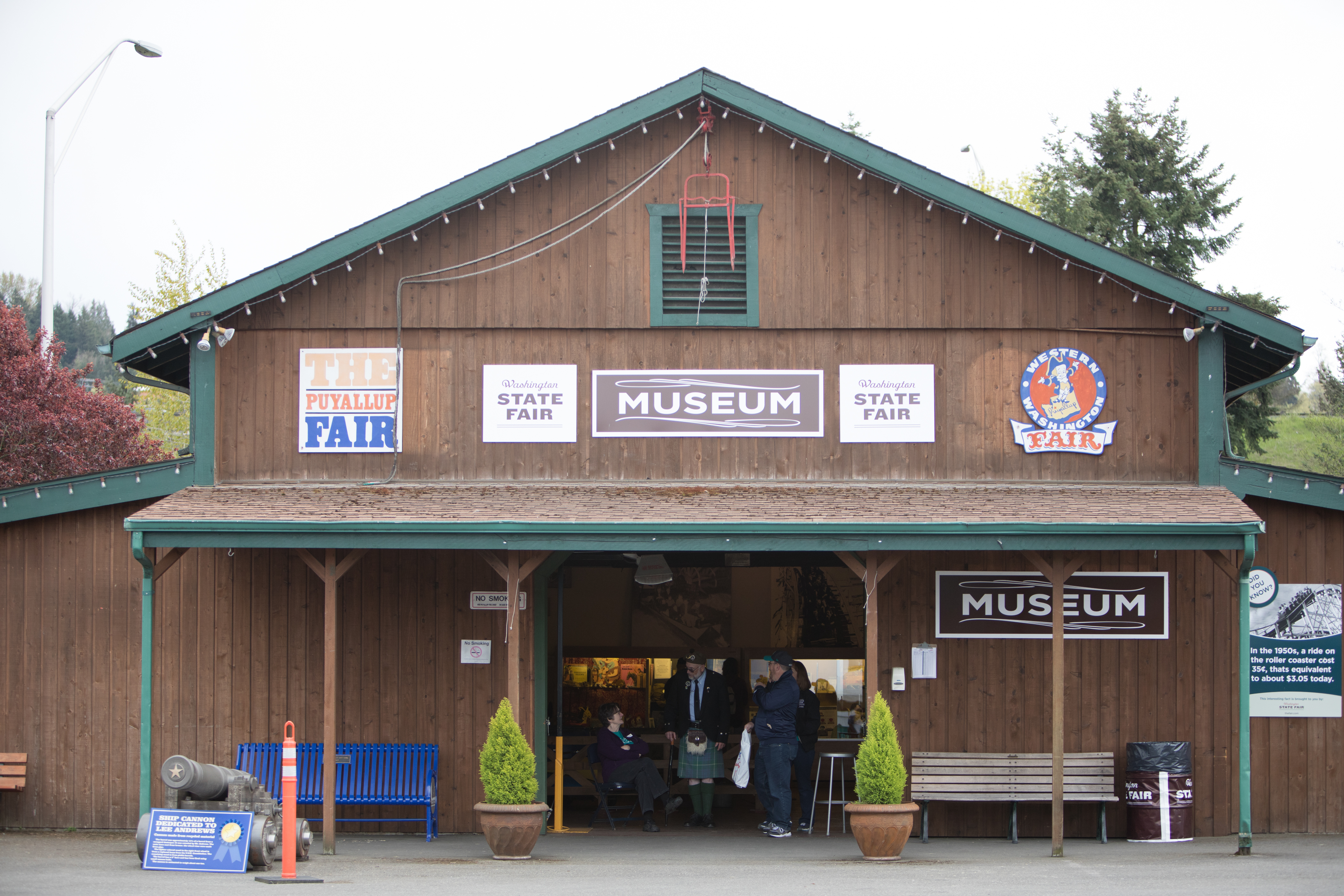 The outside of The Fair Museum, a wooden a-frame building with a green awning.