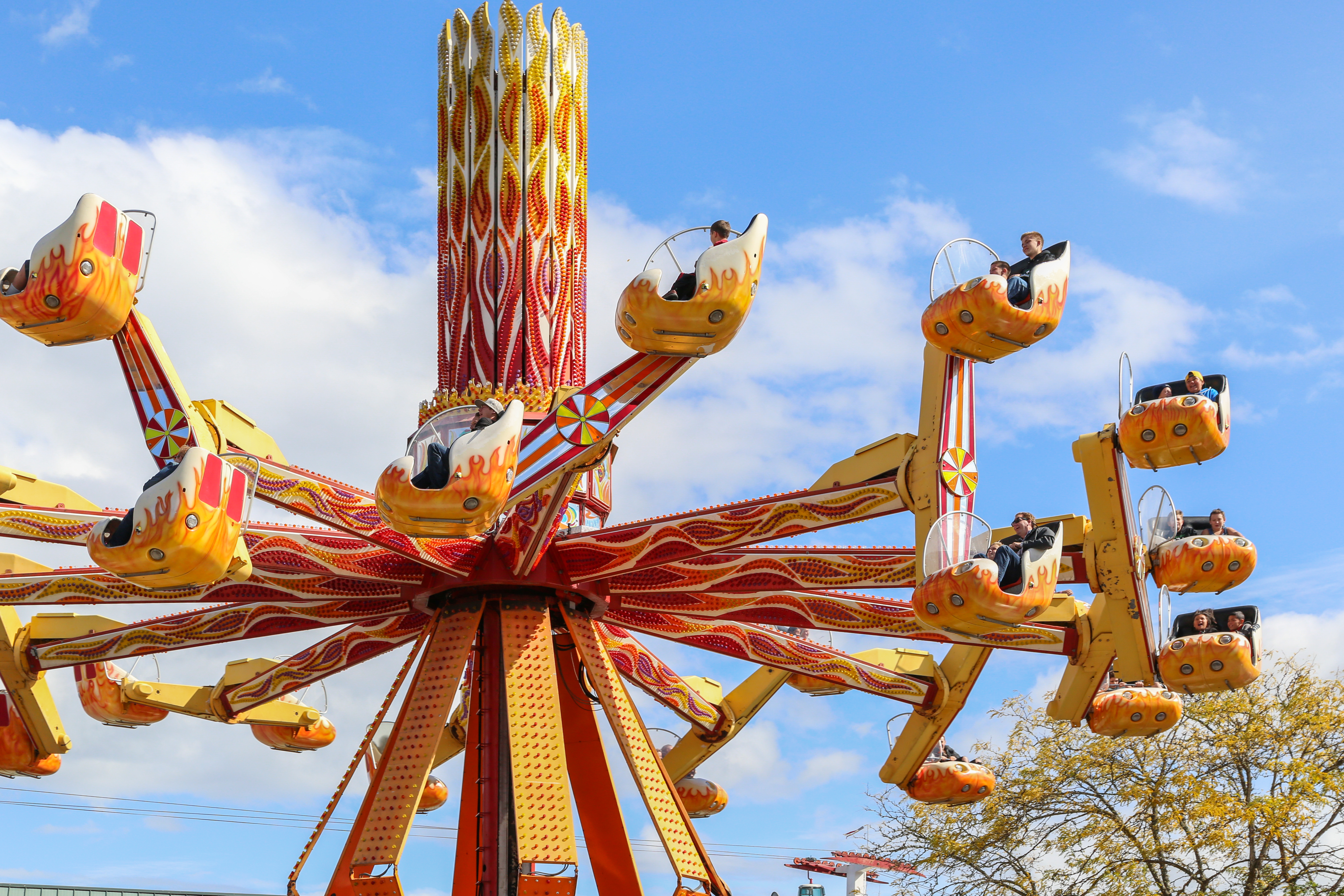 Guests ride the Inferno, an orange and yellow ride, spinning horizontally with top and bottom cars on that also spin on a separate vertical axis.