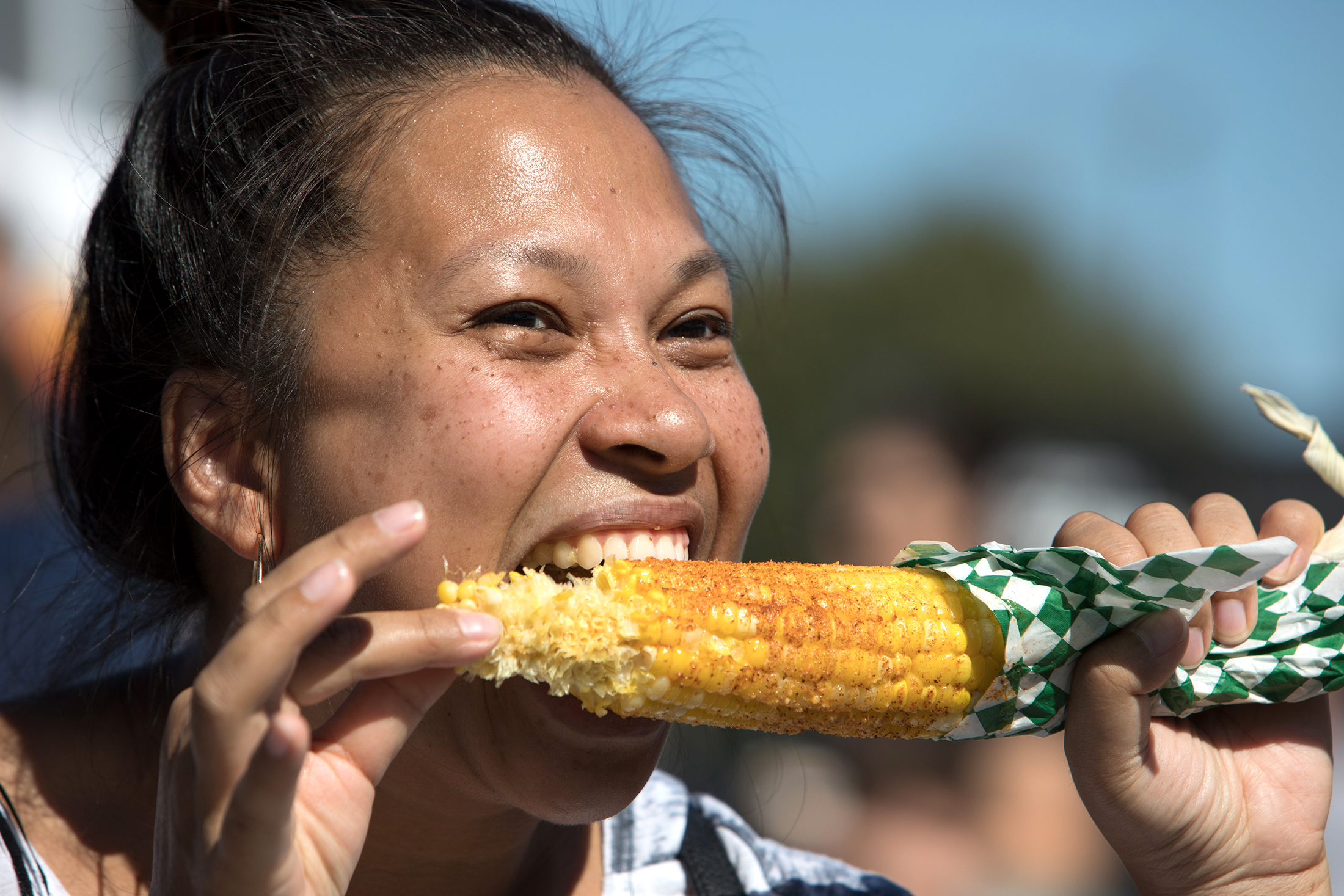 A woman eating an ear of corn.