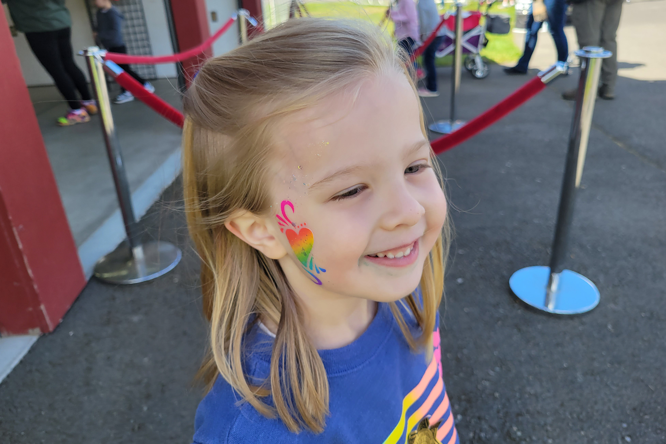 A girl with a rainbow heart painted on her face.