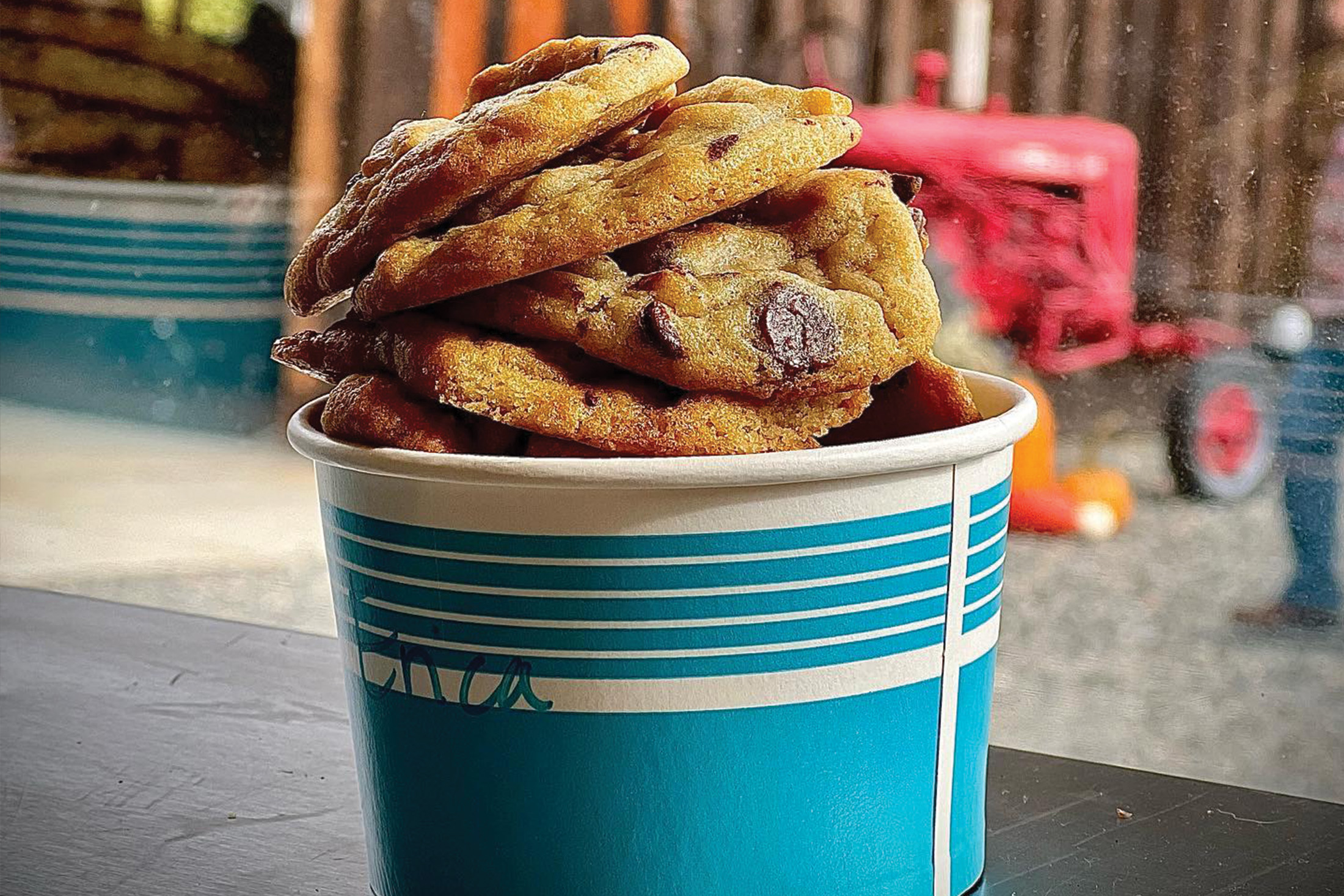 A tall stack of chocolate chip cookies in a paper bowl.