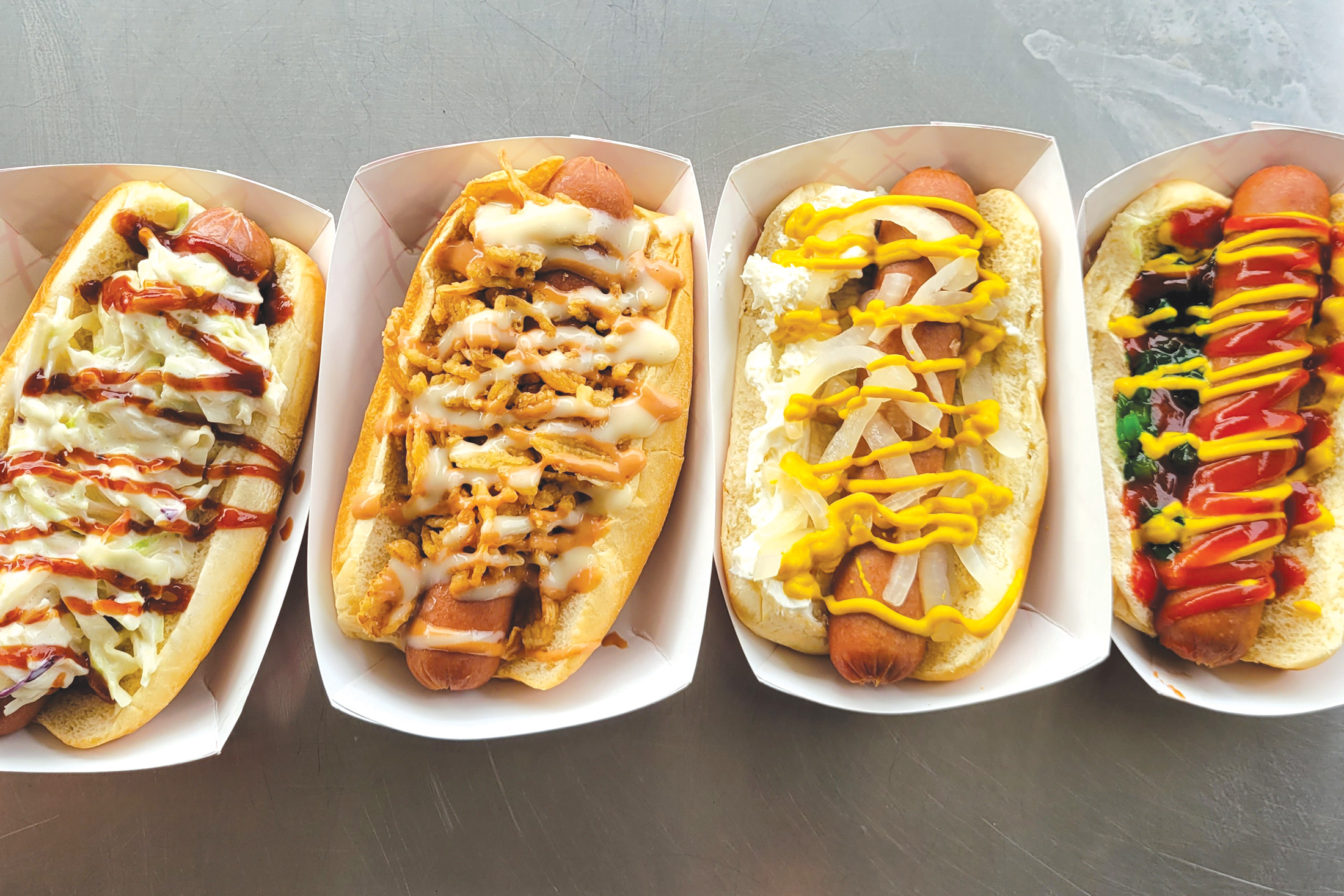 A row of hot dogs with various condiments and sauces.