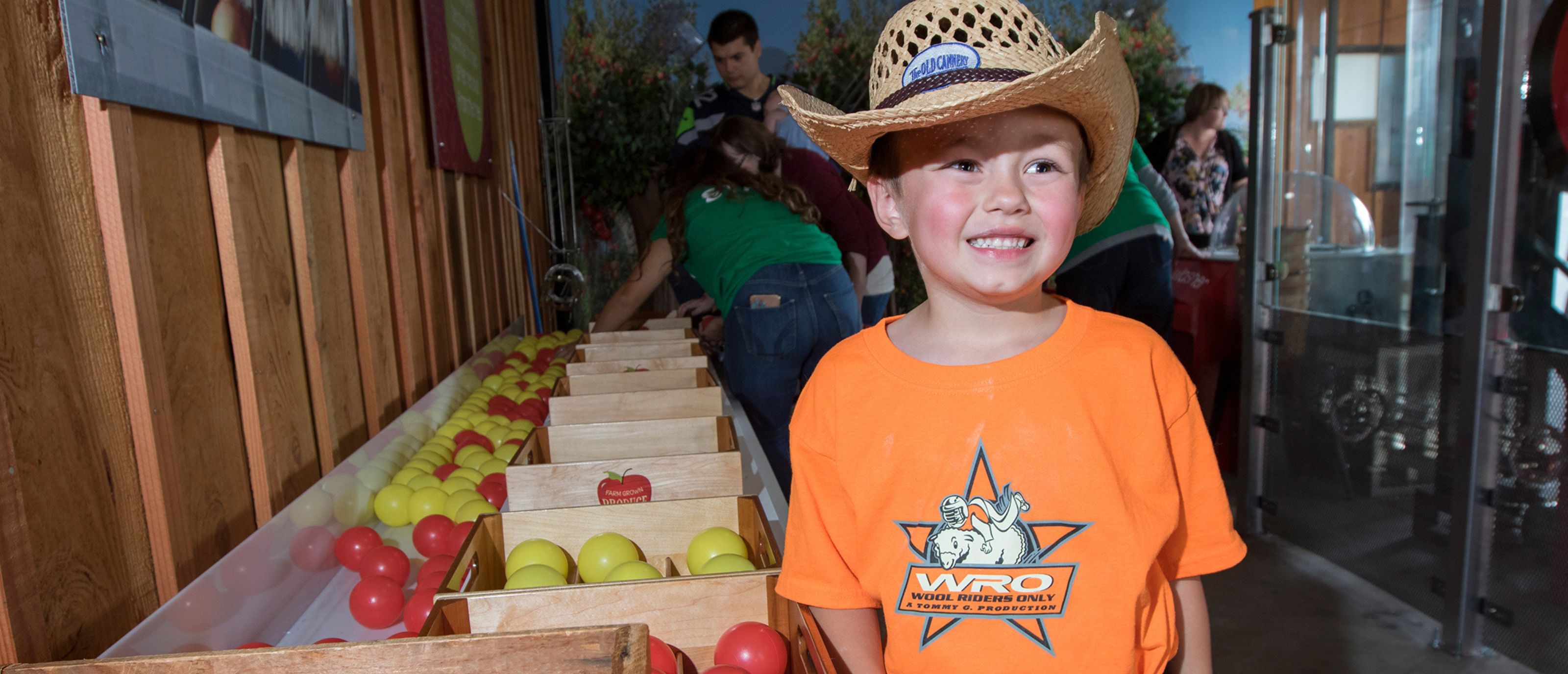 Little Boy at the Farm at Sillville wearing a cowboy hat and orange shirt