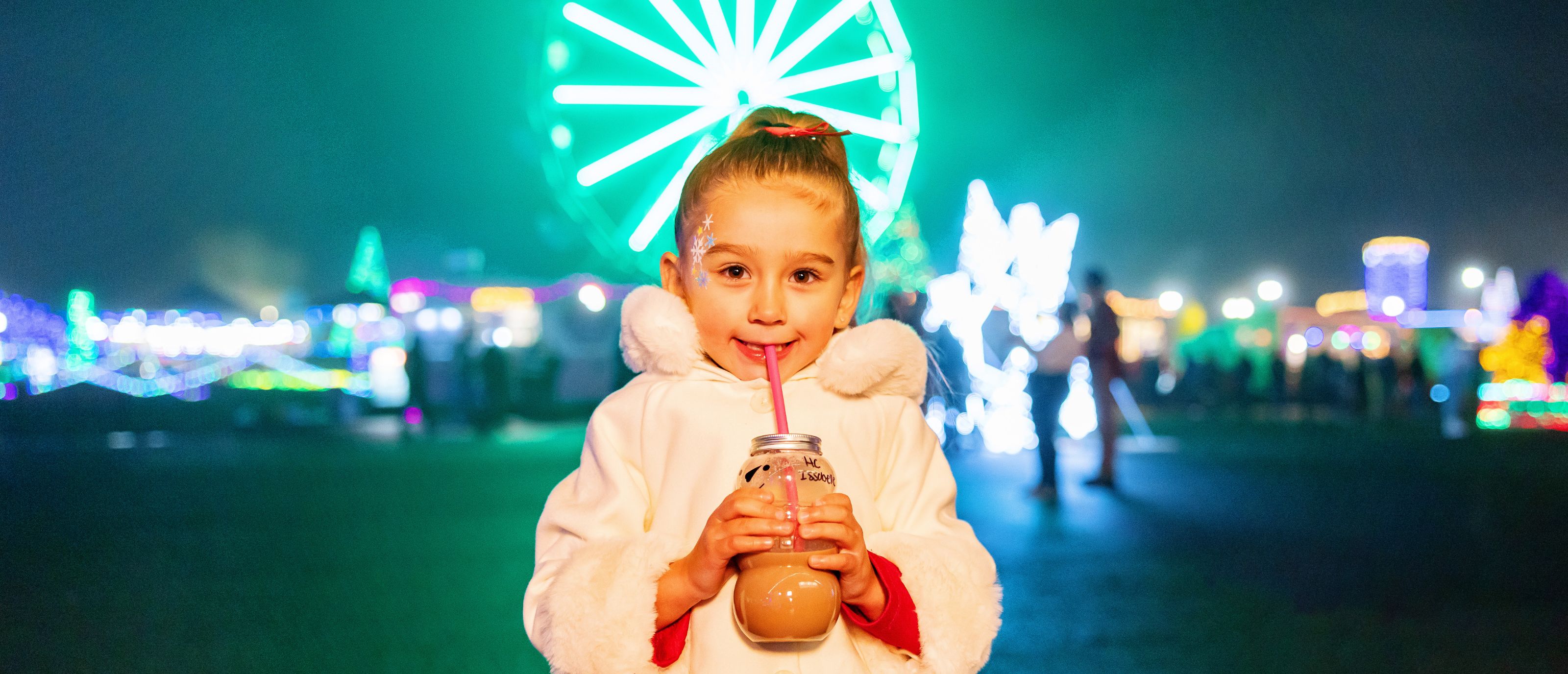 Little Girl drinking coco in front of Wonder Wheel at Holiday Magic