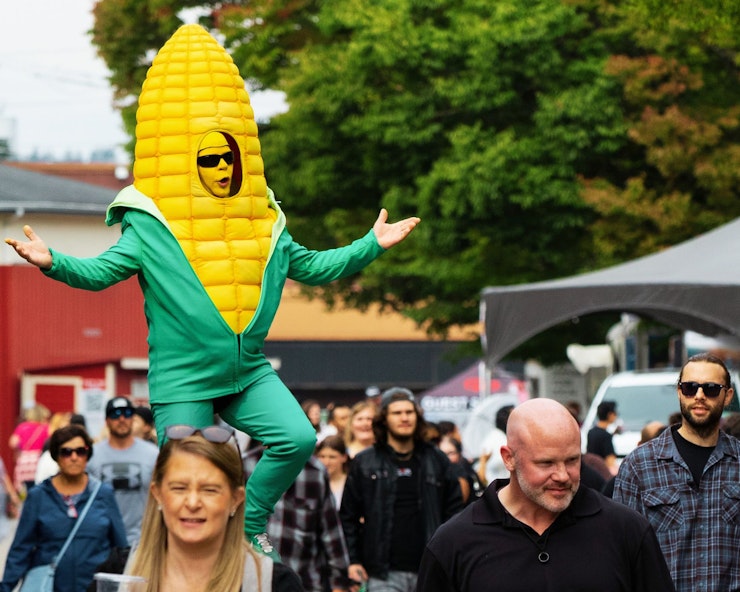 Man dressed as a giant corn on the cob, riding a unicycle