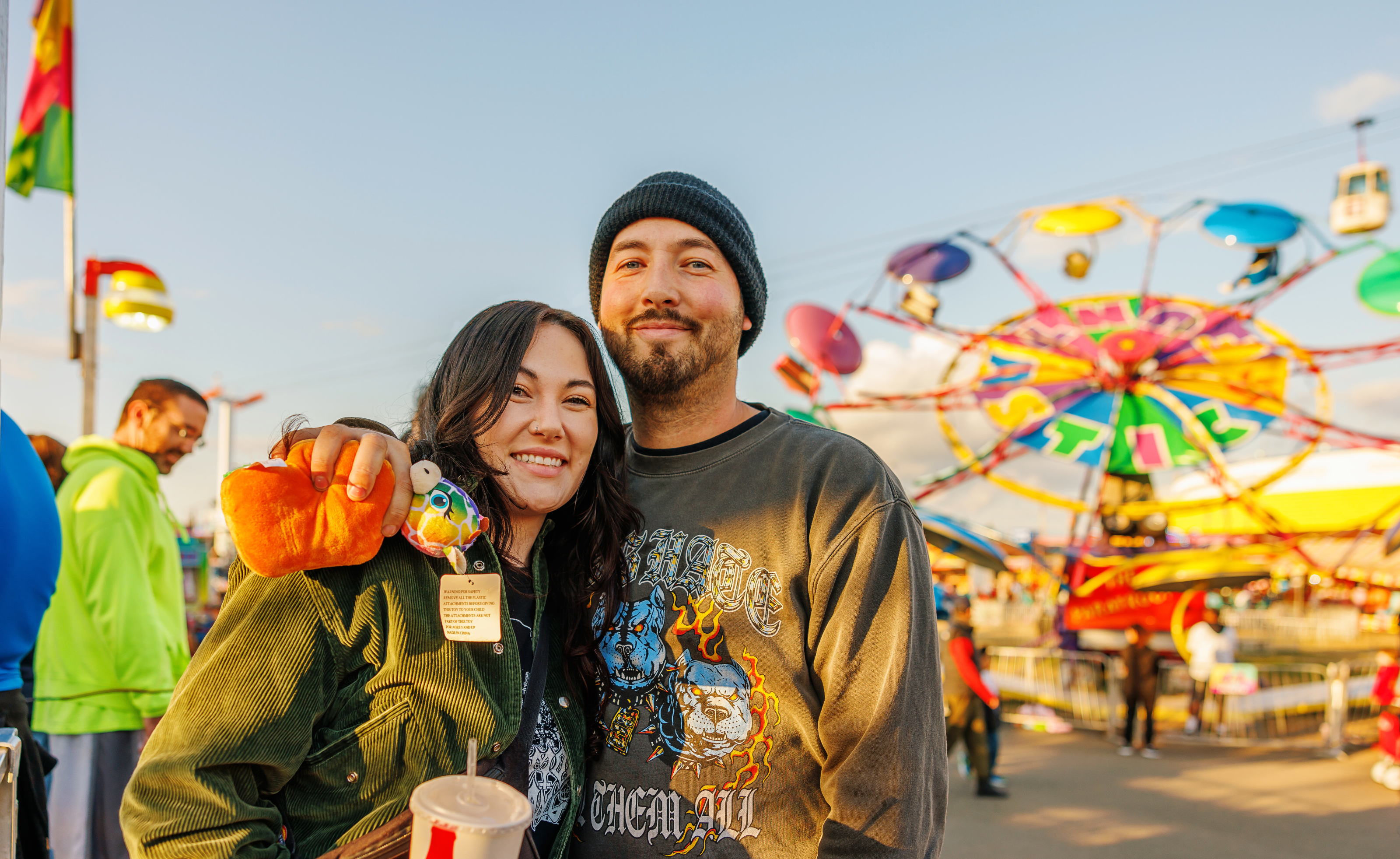 couple standing in carnival with ride going behind them
