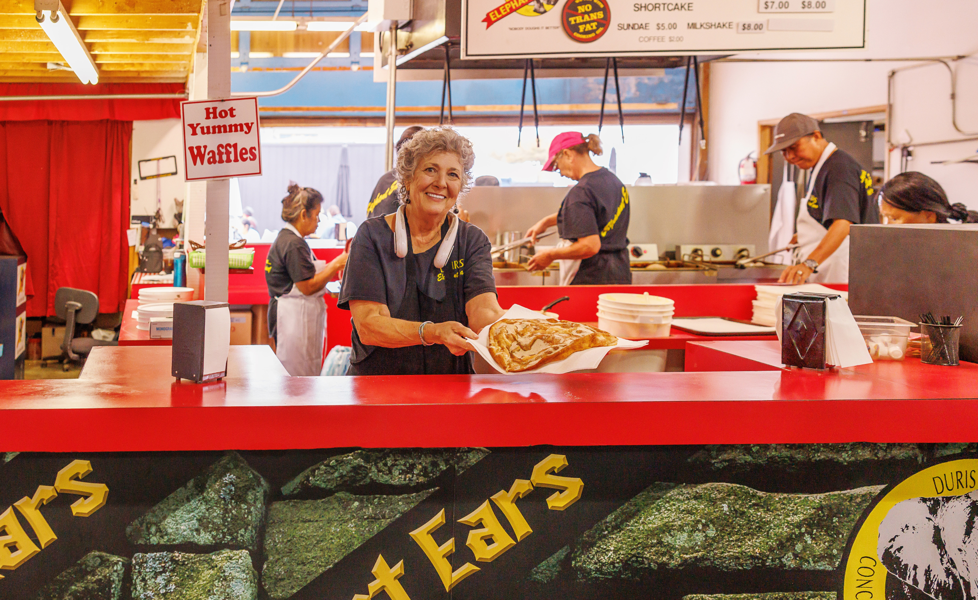 Women working at Duris Elephant Ear booth holding out elephant ear to the camera