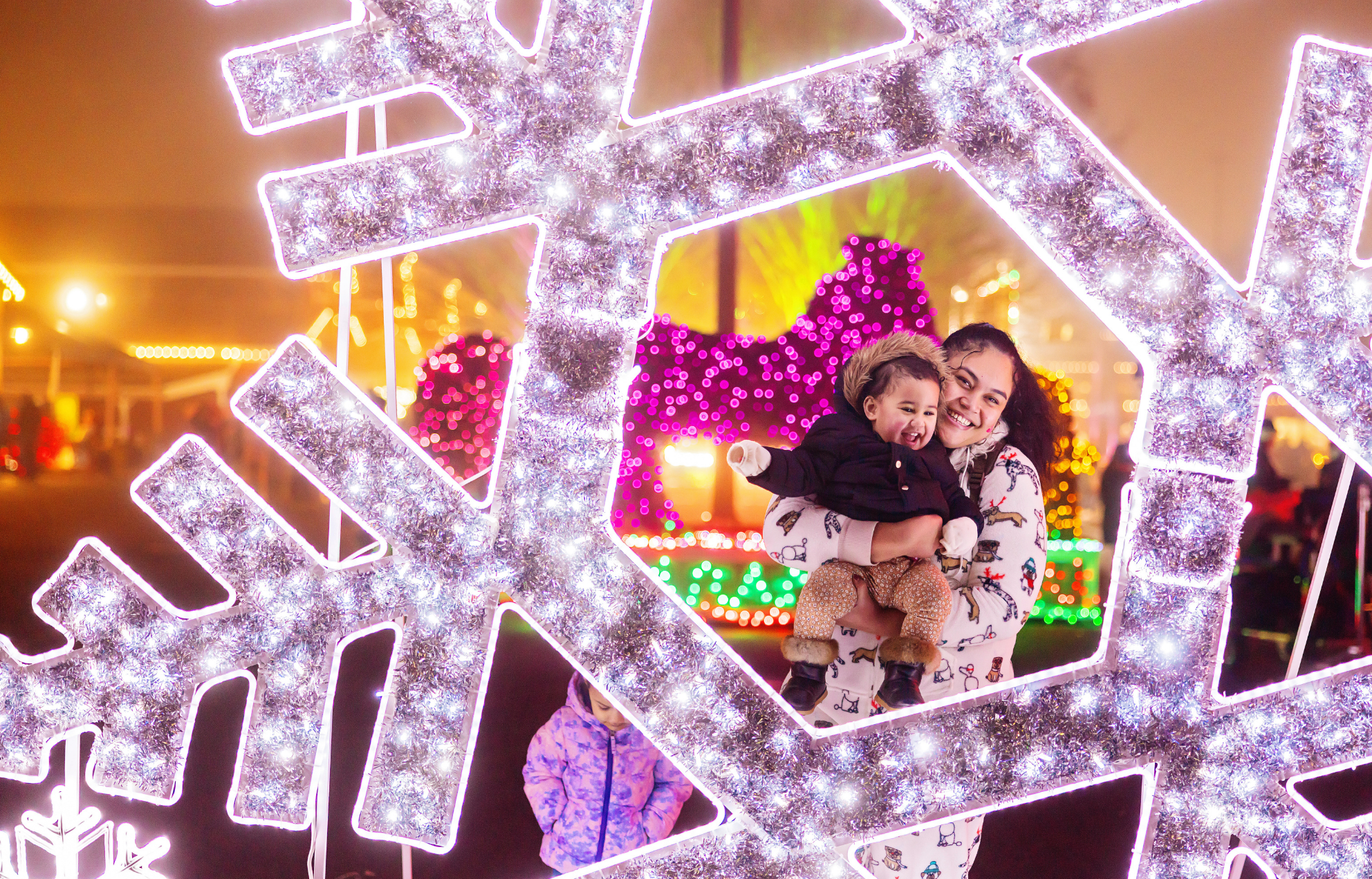 A mom and her baby in a light-up snowflake display