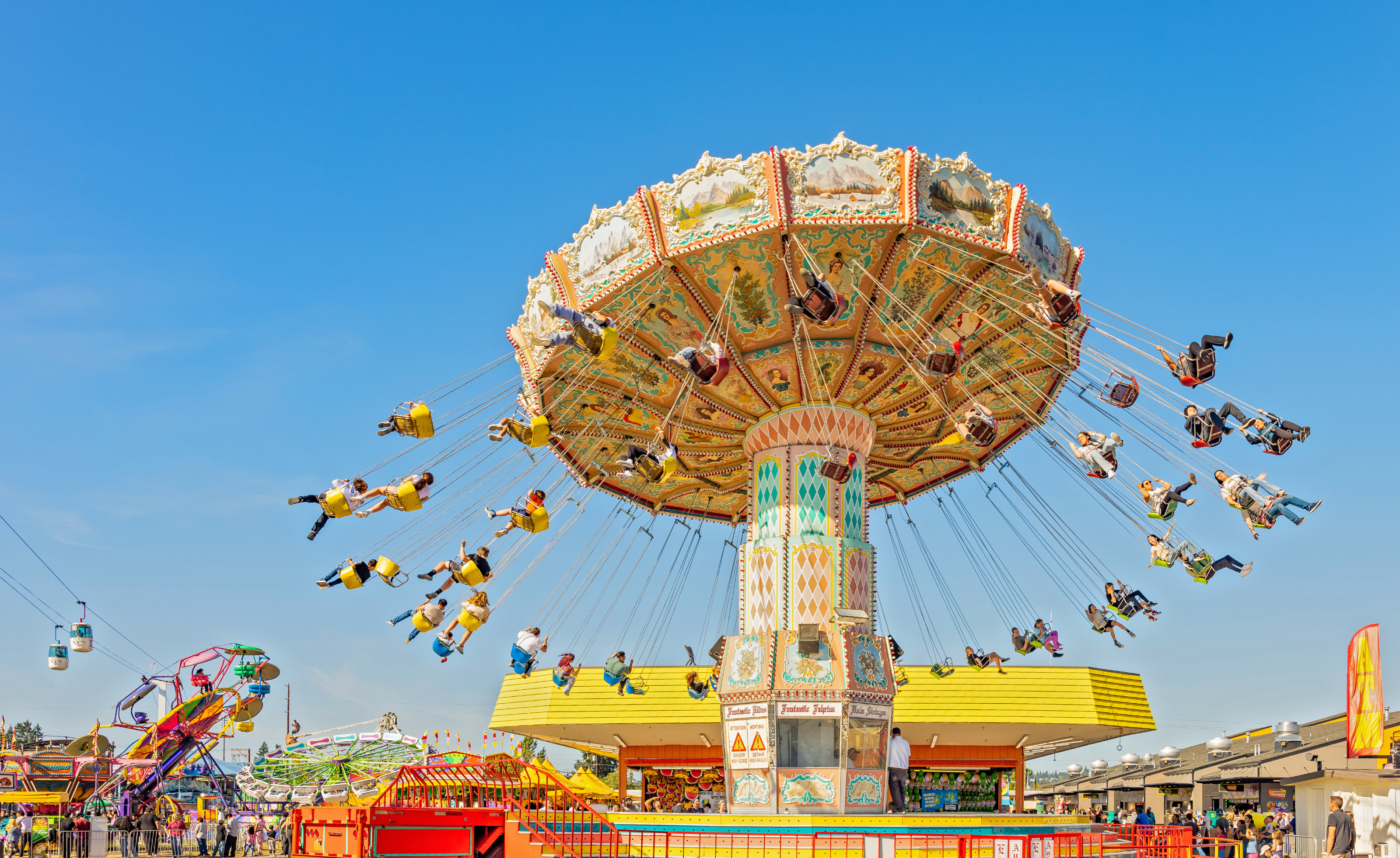 A photo of a large swing ride at the fair with a beautiful blue sky behind it