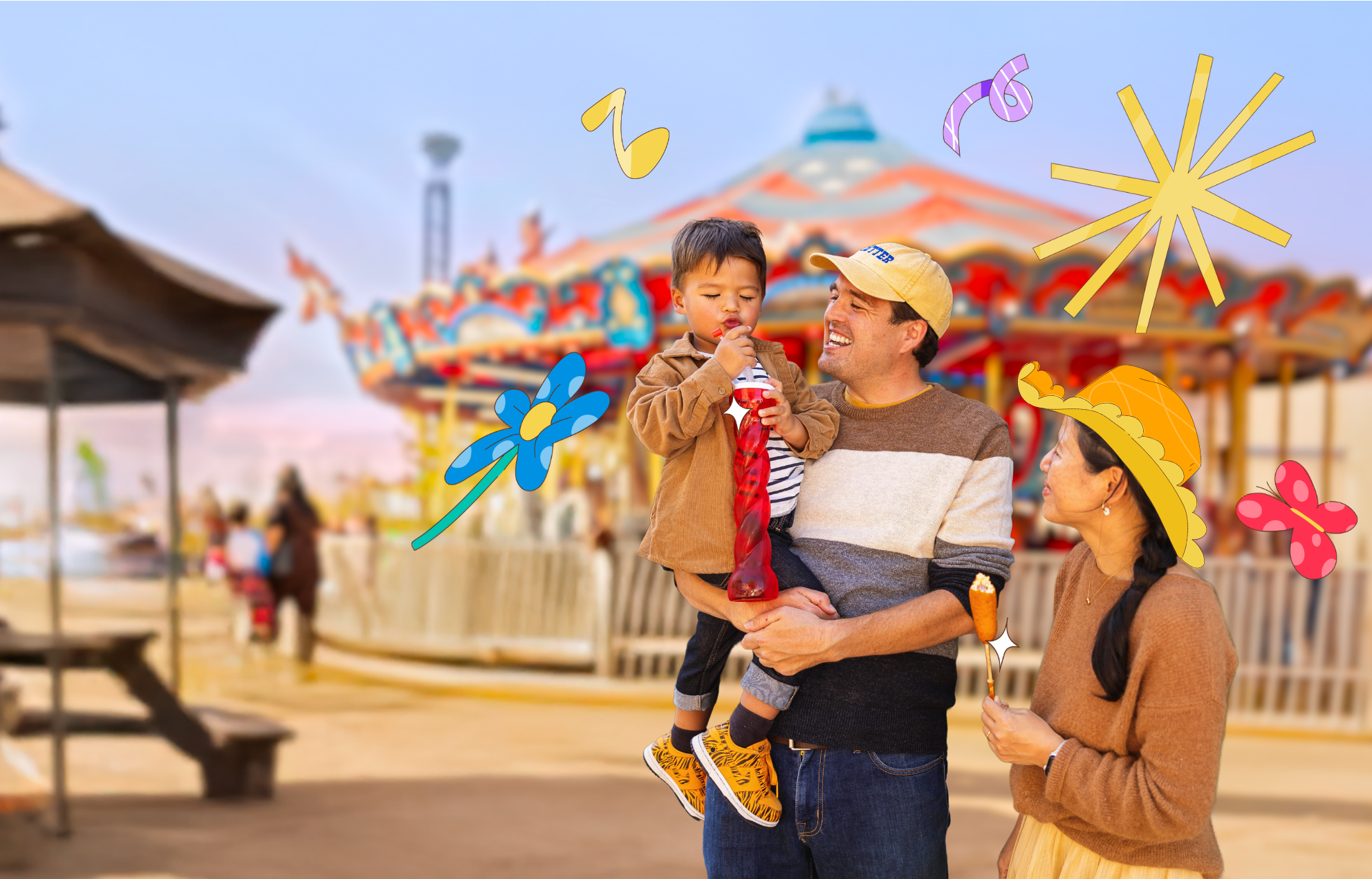 A child and his parents enjoy some snacks in front of the carousel with colorful illustrations surrounding them.
