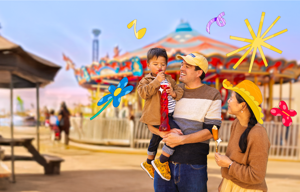 A child and his parents enjoy some snacks in front of the carousel with colorful illustrations surrounding them.