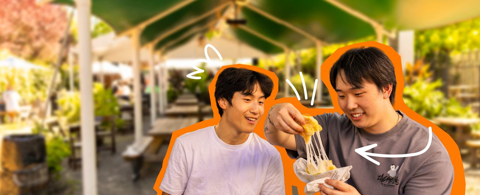 Two men holding plates of food smiling, looking at one of them stretching the cheese on his meal.