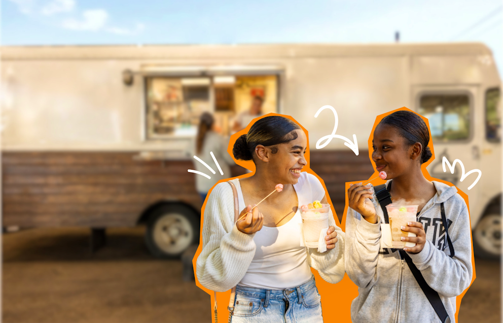 Two teens smiling at each other enjoy sparkling drinks with candy while standing in front of a food truck.
