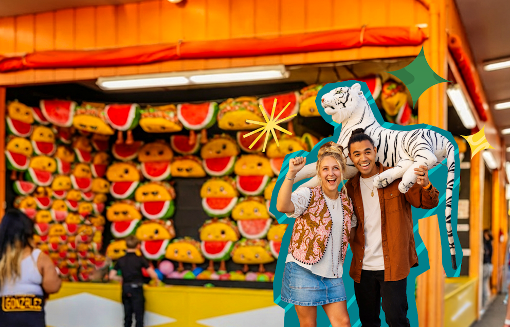 A couple holding up a prize plush tiger they won at a game booth.