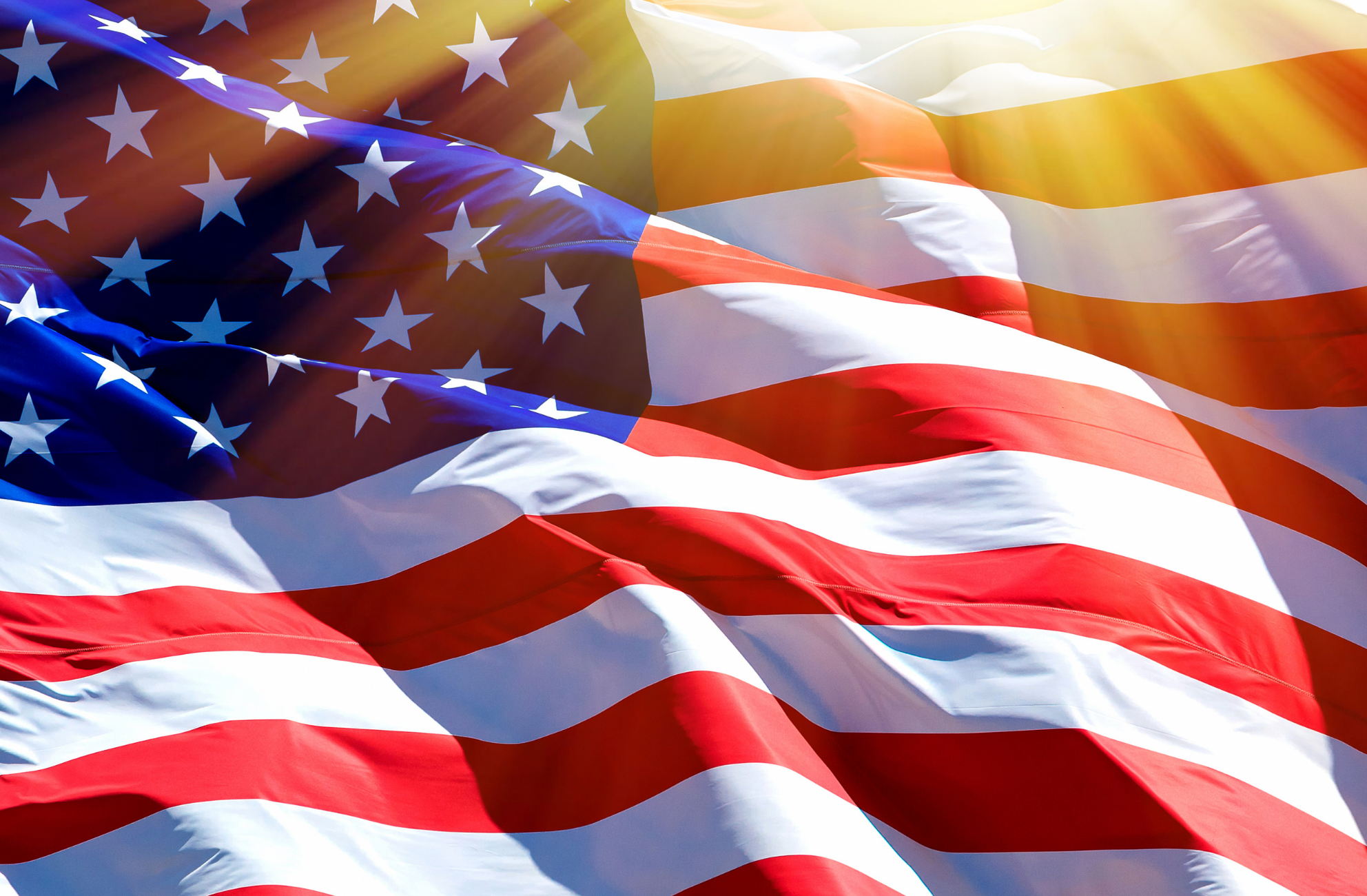 A graphic of a waving American flag with a ray of sunshine over it.