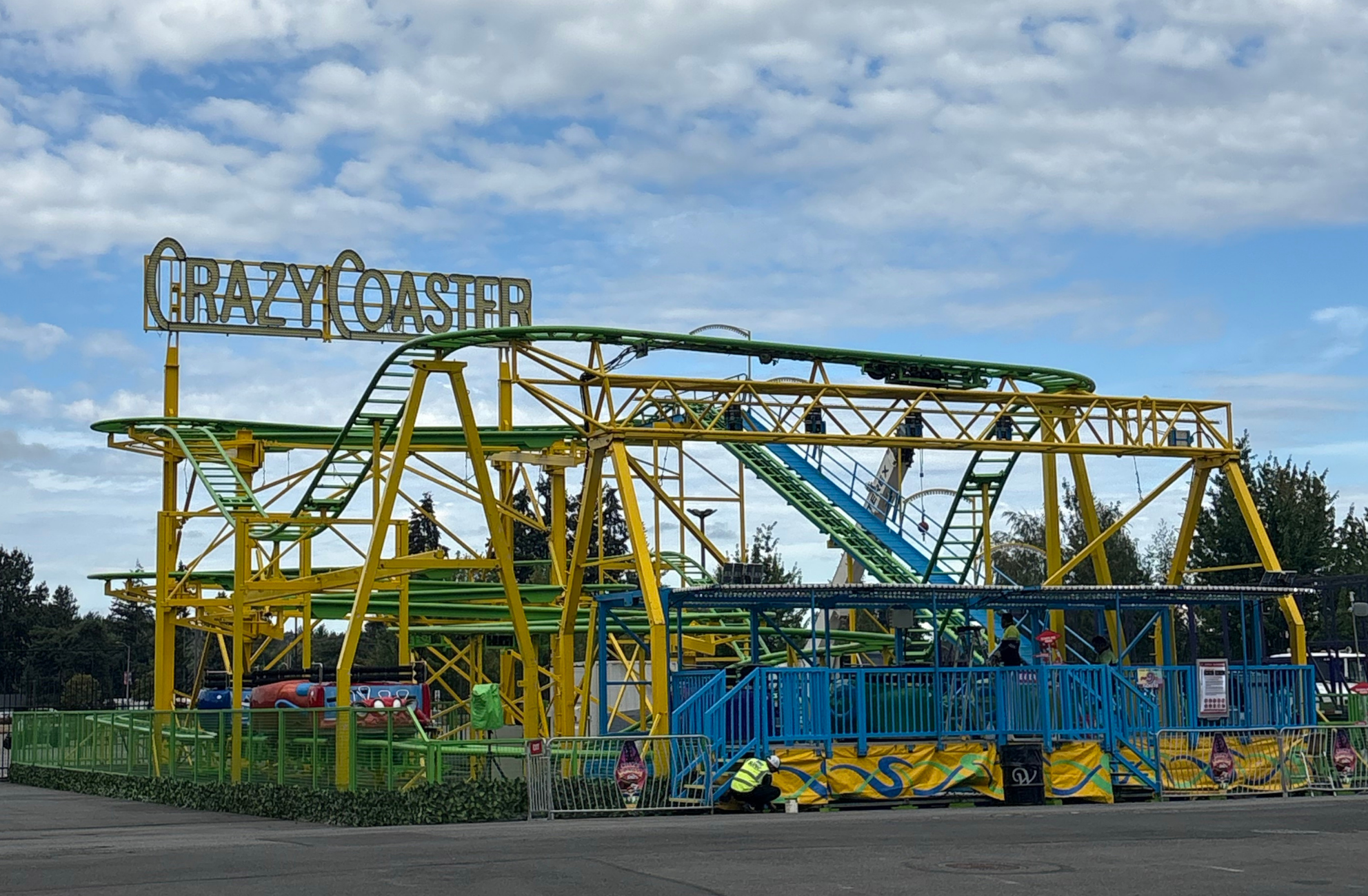 The Crazy Coaster, a tall yellow and green, metal roller coaster with tall, clamshell cars that take you along a twisting track.