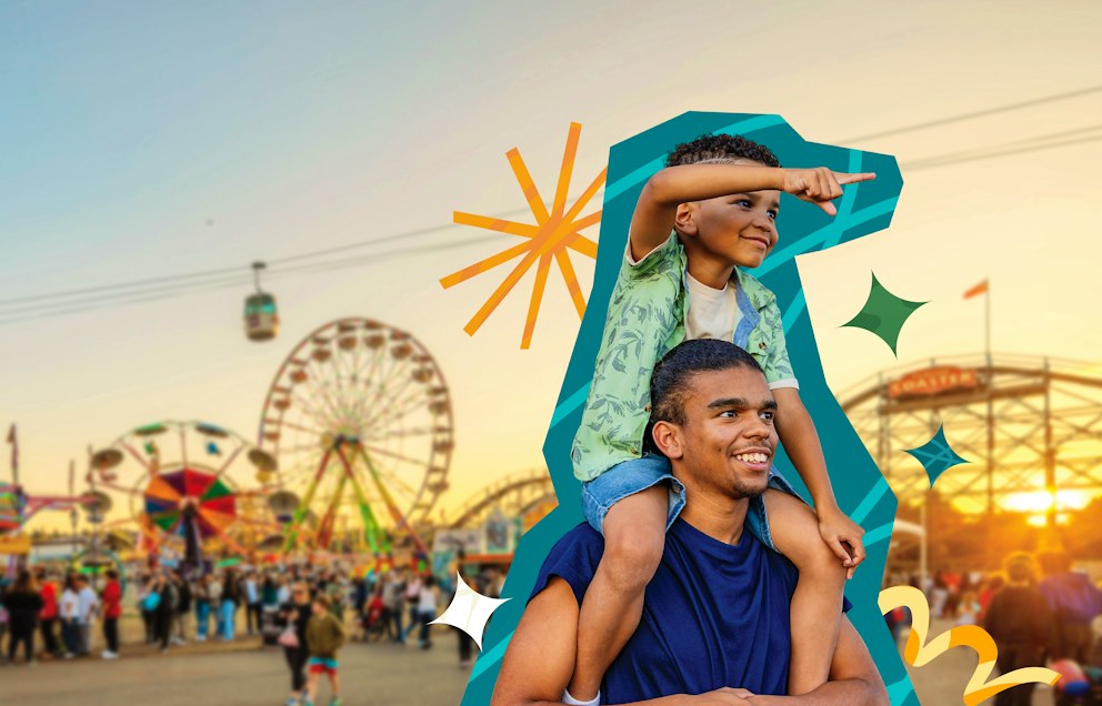 A little brother sits atop his big brother's shoulders as they walk through the Fair at sunset.