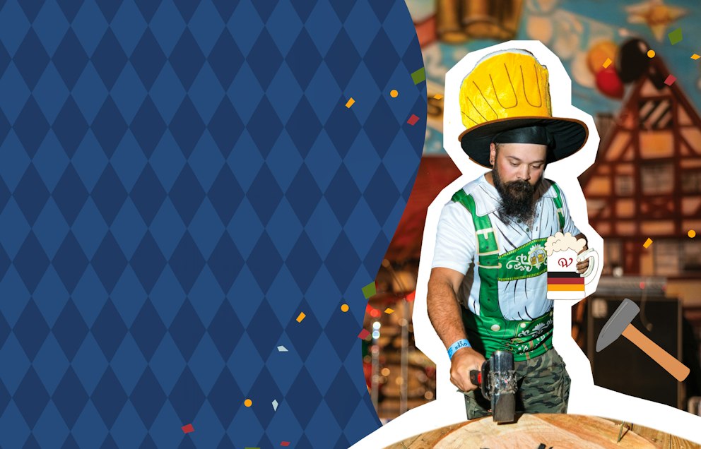 A bearded man in a large yellow hat and green lederhosen plays Hammerschlagen while holding an illustrated image of a beer.