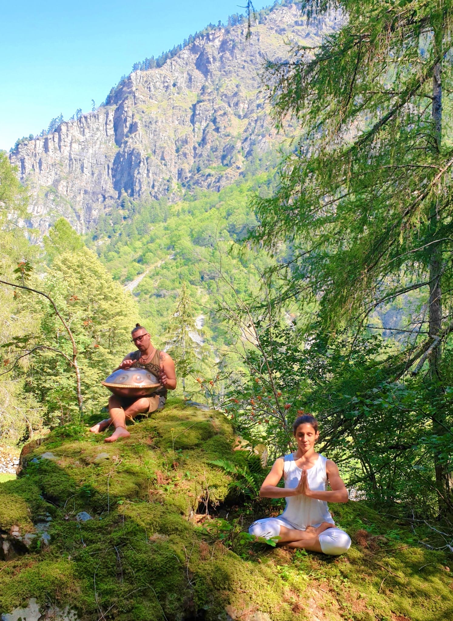 Persona in posizione yoga e persona che suona uno strumento nel bosco