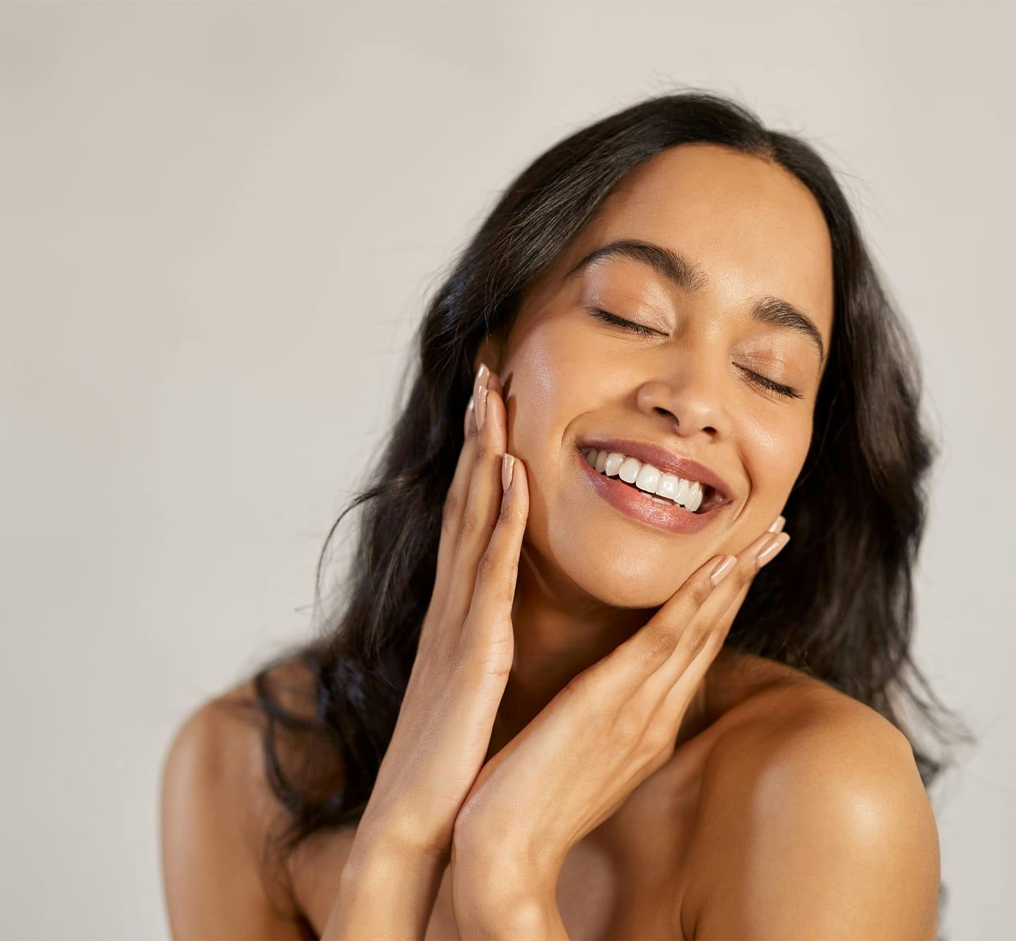 woman smiling with eyes closed touching the sides of her face