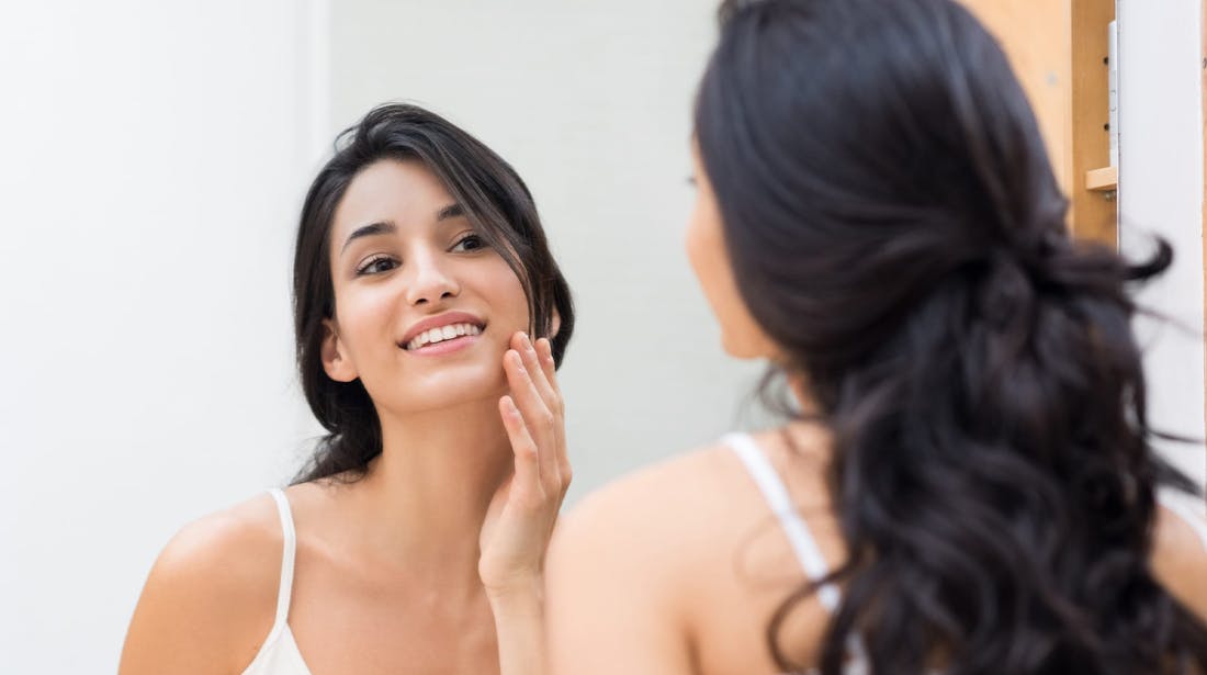 woman applying cream to face