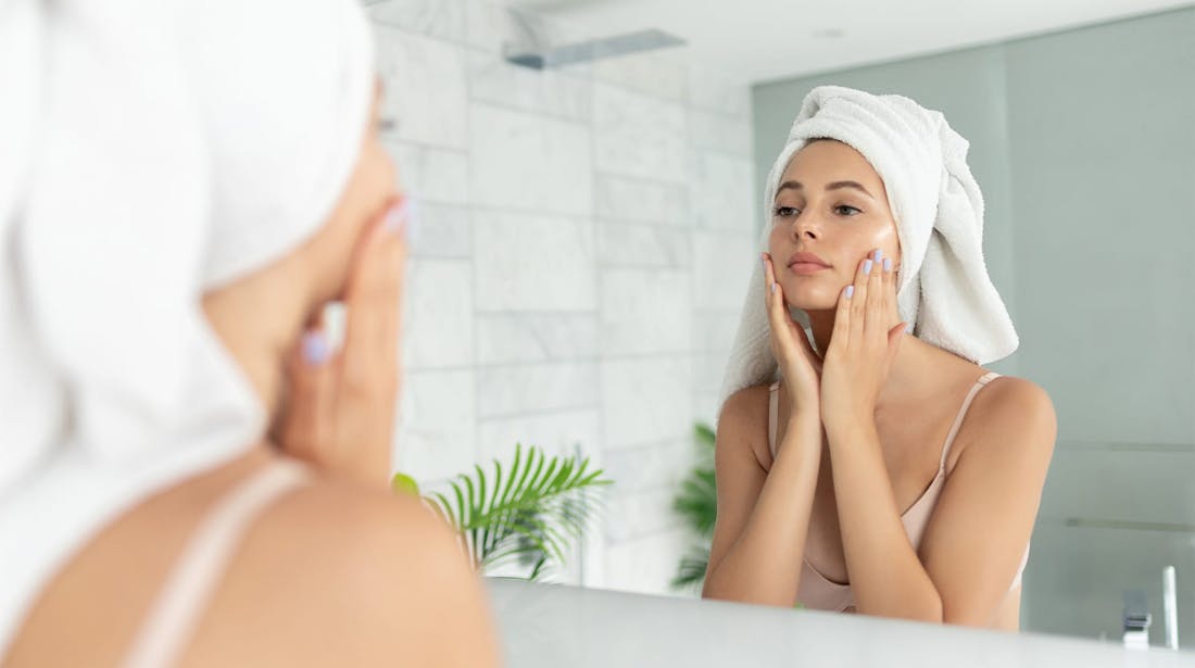 woman applying skin product after shower
